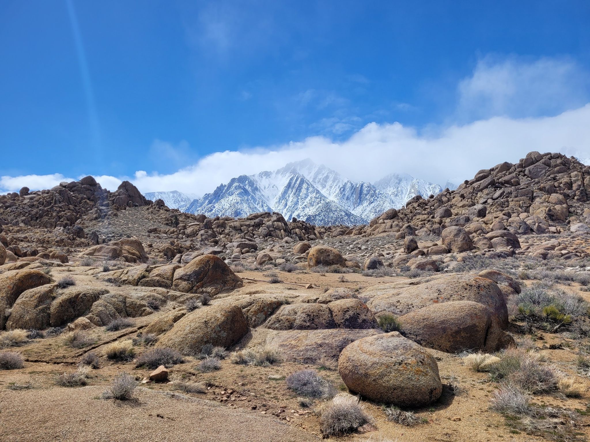 Rocky desert terrain with large boulders and distant snow-capped mountains. - Upper Alabama Hills Trail to Cyclops Skull Arch