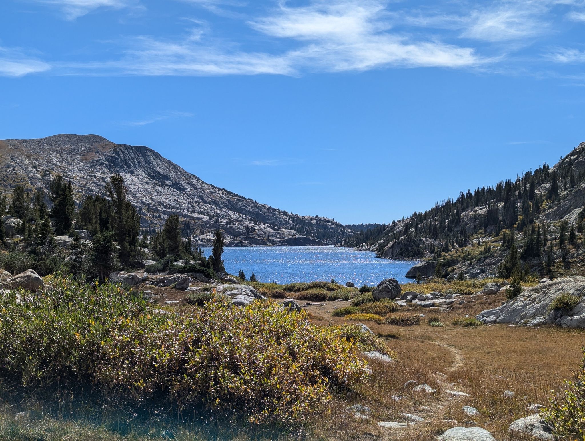 Blue lake nestled between mountains, surrounded by trees under a clear sky. - Titcomb Basin via Pole Creek Trail and Crooks Lakes Loop