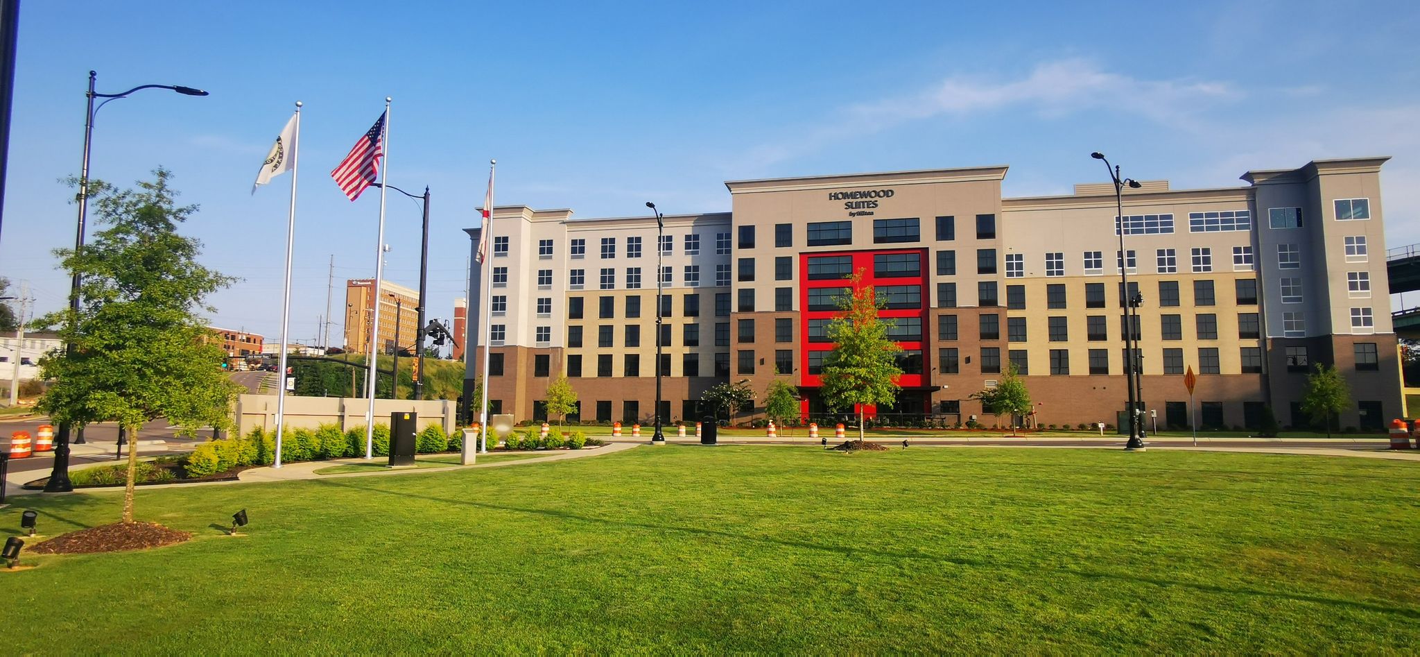 Large modern building with red accents, green lawn, and flags under blue sky. - Black Warrior River – Parker-Haun Park loop from Tuscaloosa