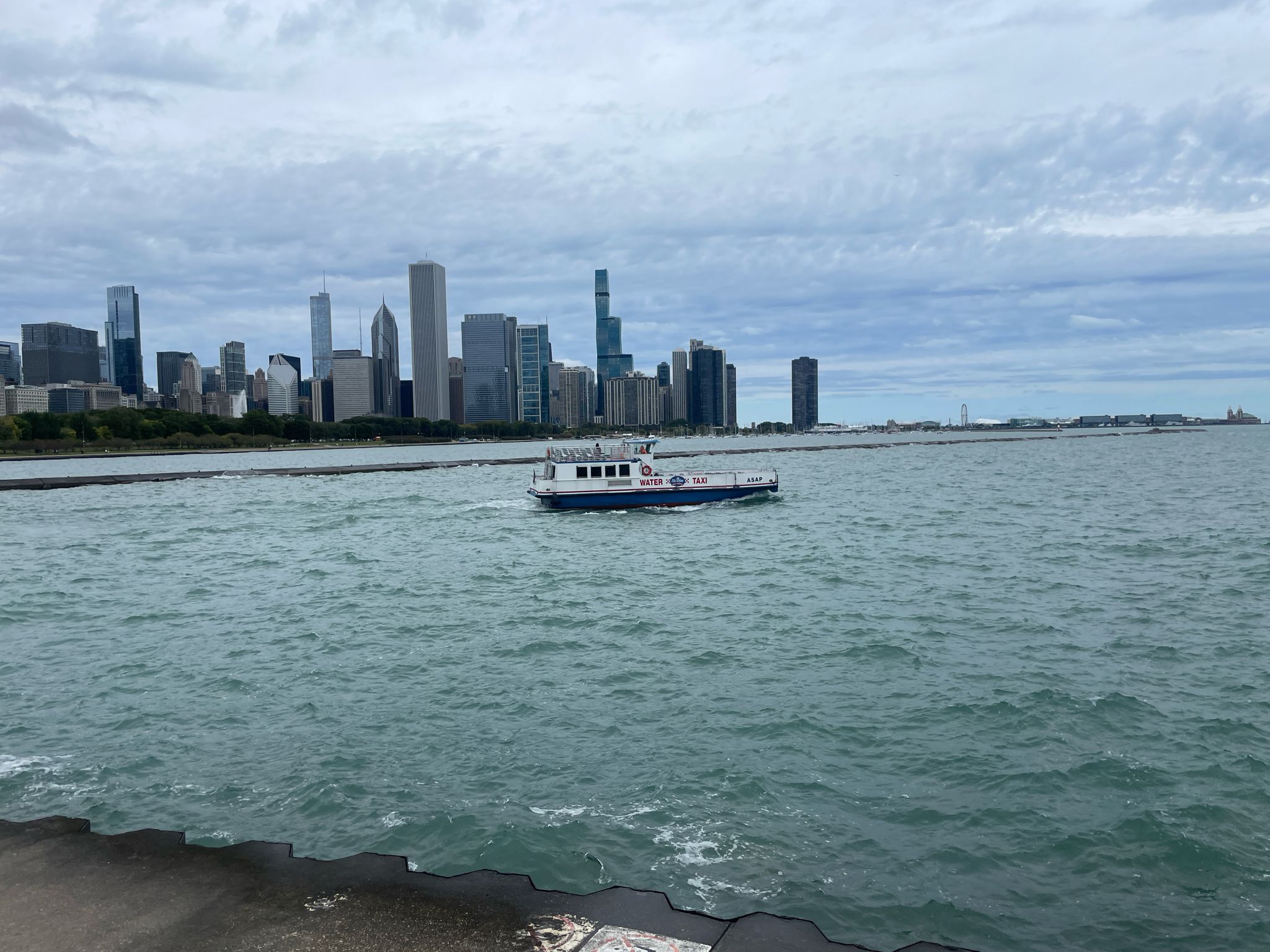 Boat on choppy water with a distant city skyline under cloudy sky. - Chicago Lakefront and Route 66 Loop