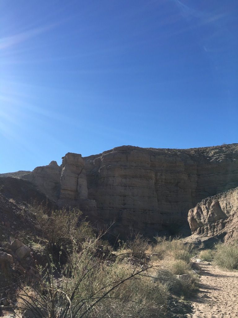 Sunlight illuminates a wide desert canyon with rocky hills and sparse vegetation. - Ladder Canyon and Painted Canyon Trail