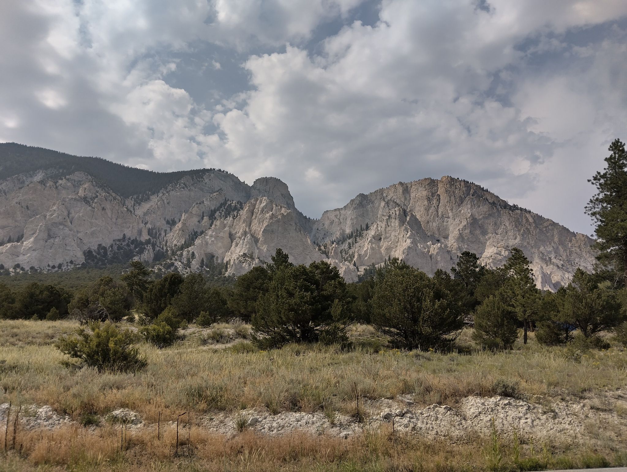 Rocky mountains under an overcast sky, with sparse trees and dry grass. - Mount Princeton Hot Springs Resort and the Chalk Cliffs from Nathrop