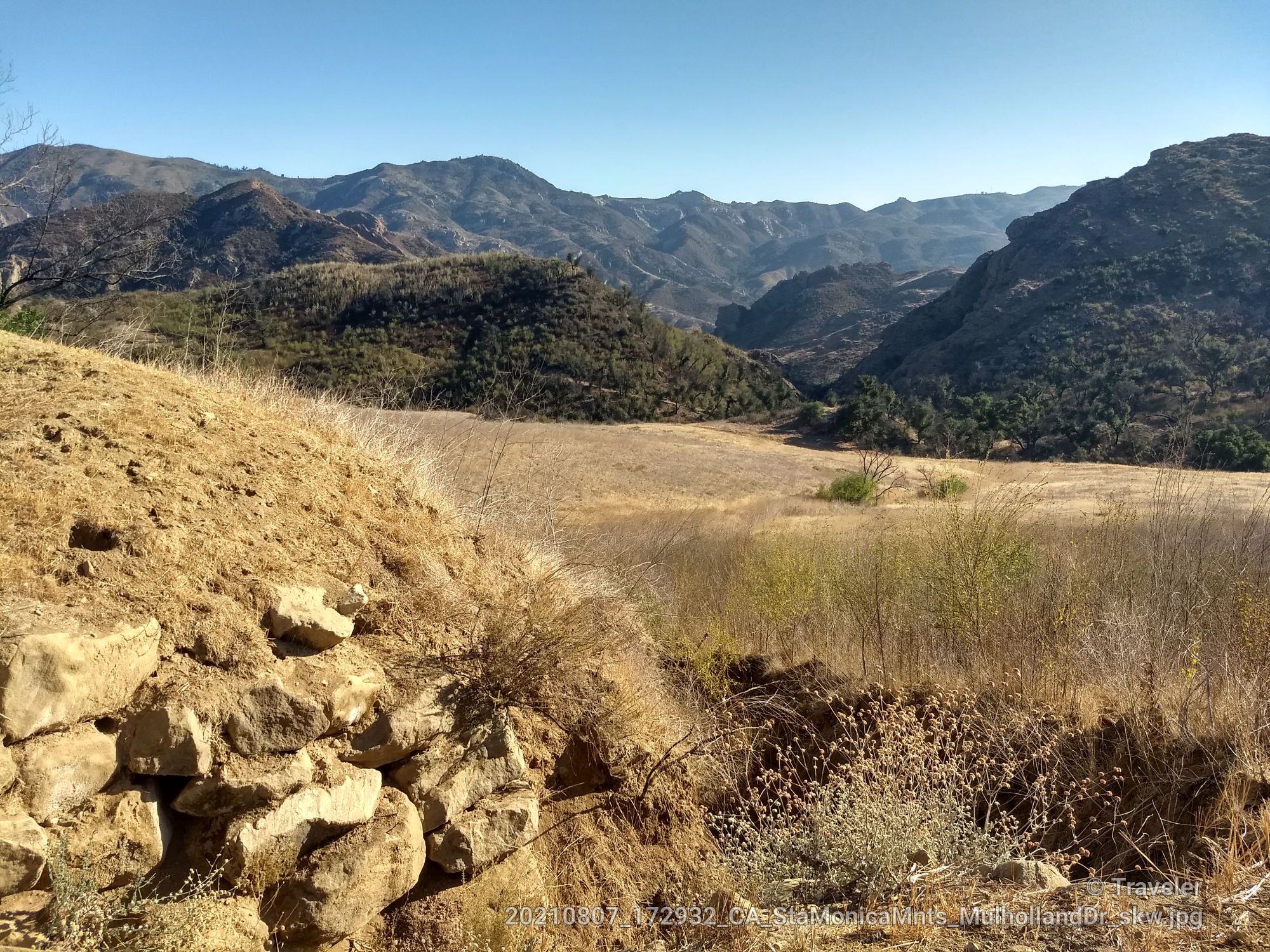 Rocky foreground overlooking a dry valley and distant rugged mountains. - Malibu Lagoon State Beach – Dan Blocker Beach loop from Chatsworth