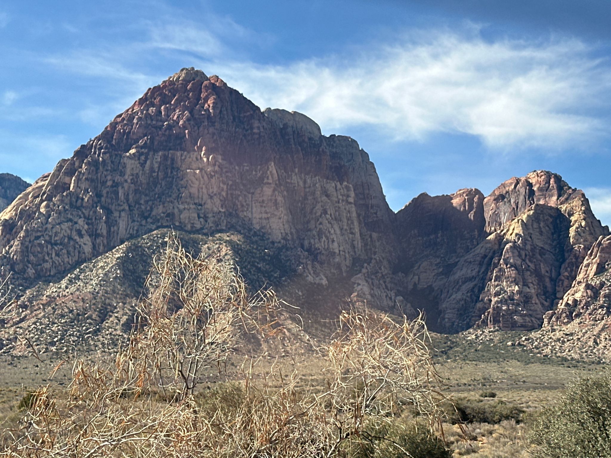 Large, rugged mountain dominates a desert landscape under a blue sky. - Red Rock Wash Overlook loop from Lower Red Rock Parking Area