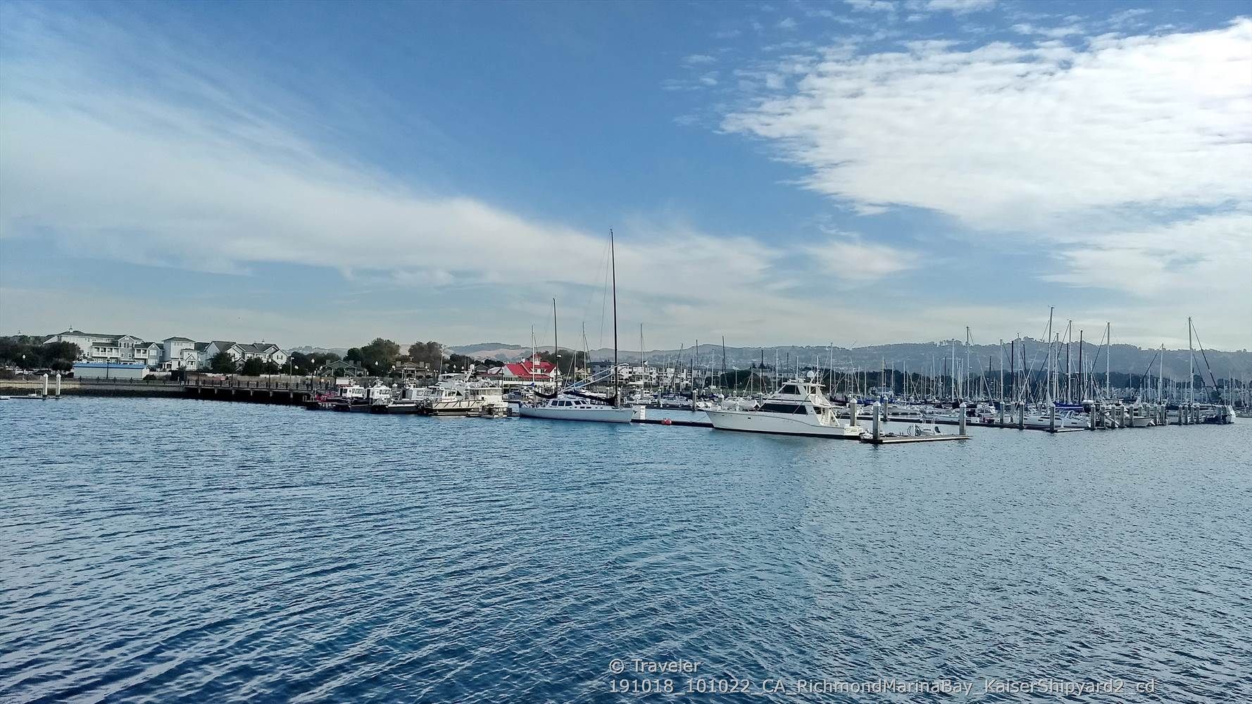 A marina filled with boats, buildings, and distant hills under a cloudy sky. - San Francisco Bay Trail: Richmond Marina Bay