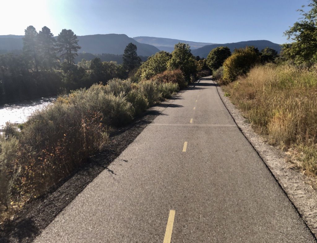 Paved path alongside a river with distant mountains under a sunny sky. - Carbondale – Satank Bridge loop from Carbondale