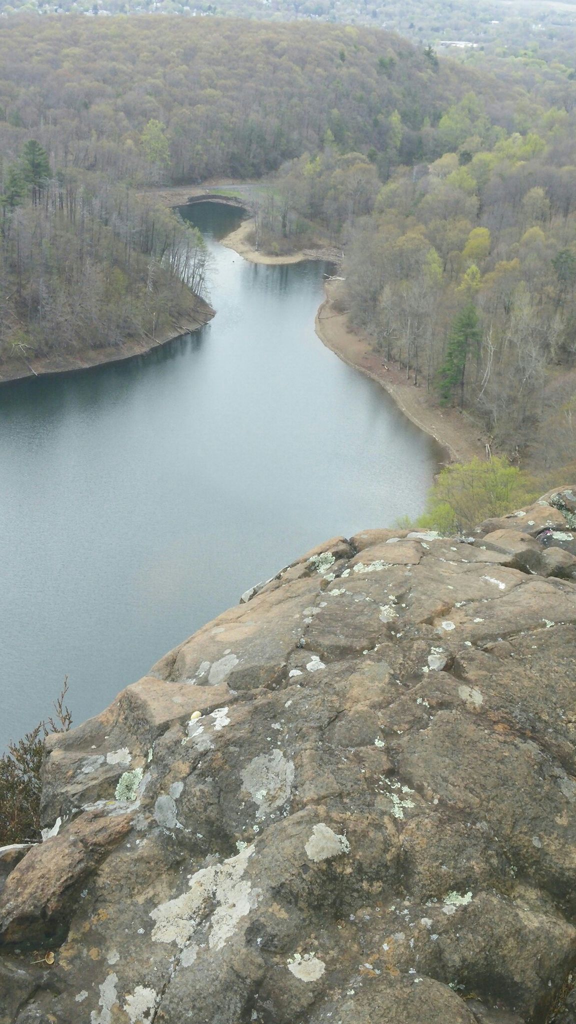 Overhead view of a winding lake from a rocky cliff, surrounded by trees. - Merimere Reservoir Loop via Metacomet Trail