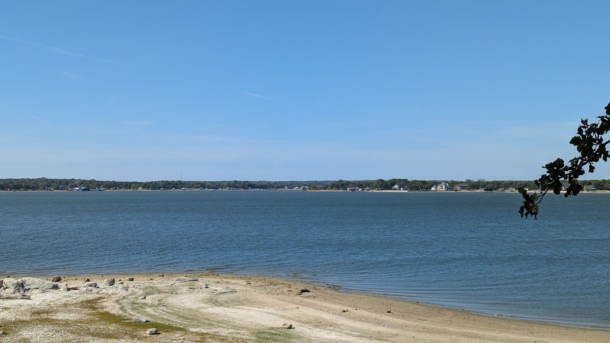 Wide blue lake with sandy shore under clear sunny sky. - Eagle Mountain Lake Loop