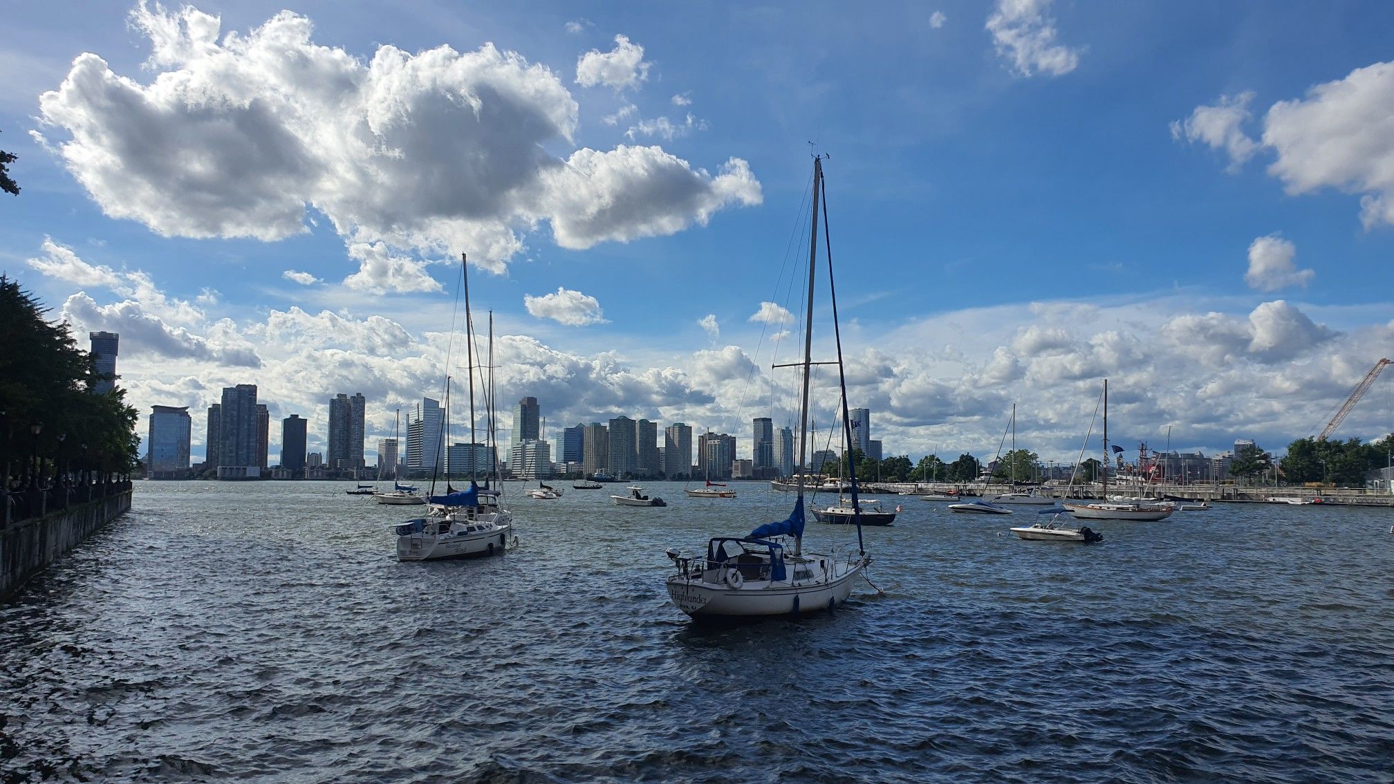 Sailboats on choppy water with a city skyline under a bright, cloudy sky. - New York City Hall loop from 9th Street