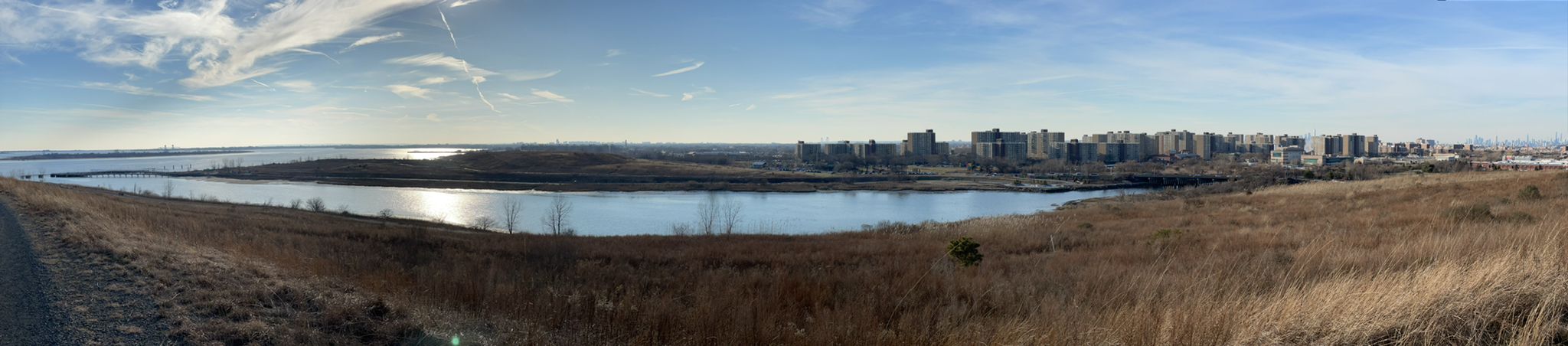 Panoramic view of a calm lake with distant city under a bright sky. - Great Blue Heron Loop