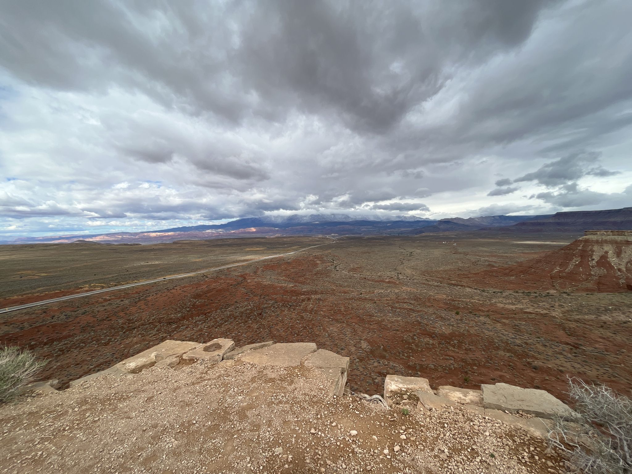 Expansive desert landscape under a dramatic cloudy sky from a high vantage. - More Cowbell Trail loop from JEM Trailhead Parking