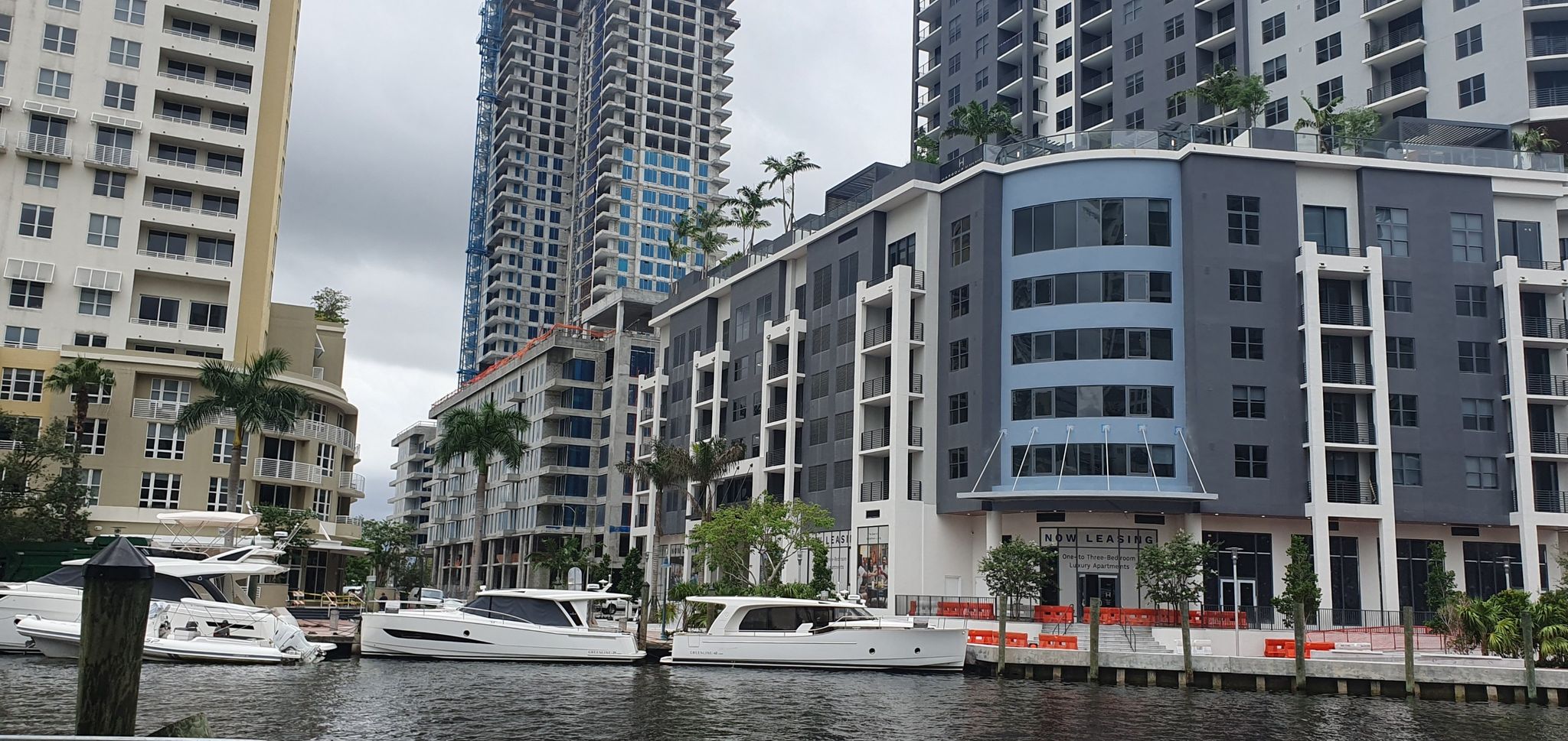 Modern buildings and boats docked along a waterway on a cloudy day. - Fort Lauderdale Riverwalk