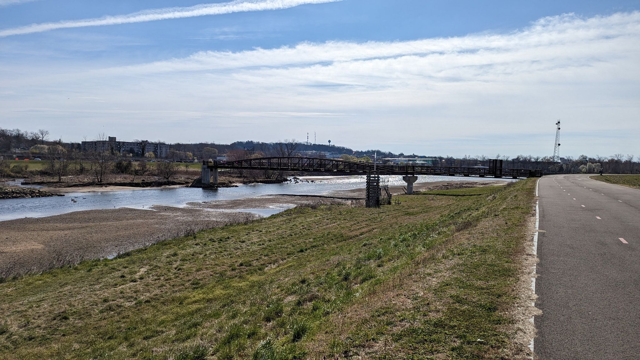 River, distant bridge, paved road, and grassy banks under a bright sky. - Northeast Branch Trail – College Park Airport loop from Washington Union Station