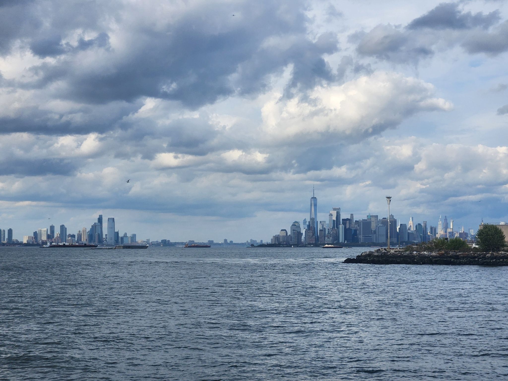 City skyline across wide water under a dramatic cloudy sky. - Plumb Beach – Belt Parkway Bike Path loop from Fort Hamilton Parkway