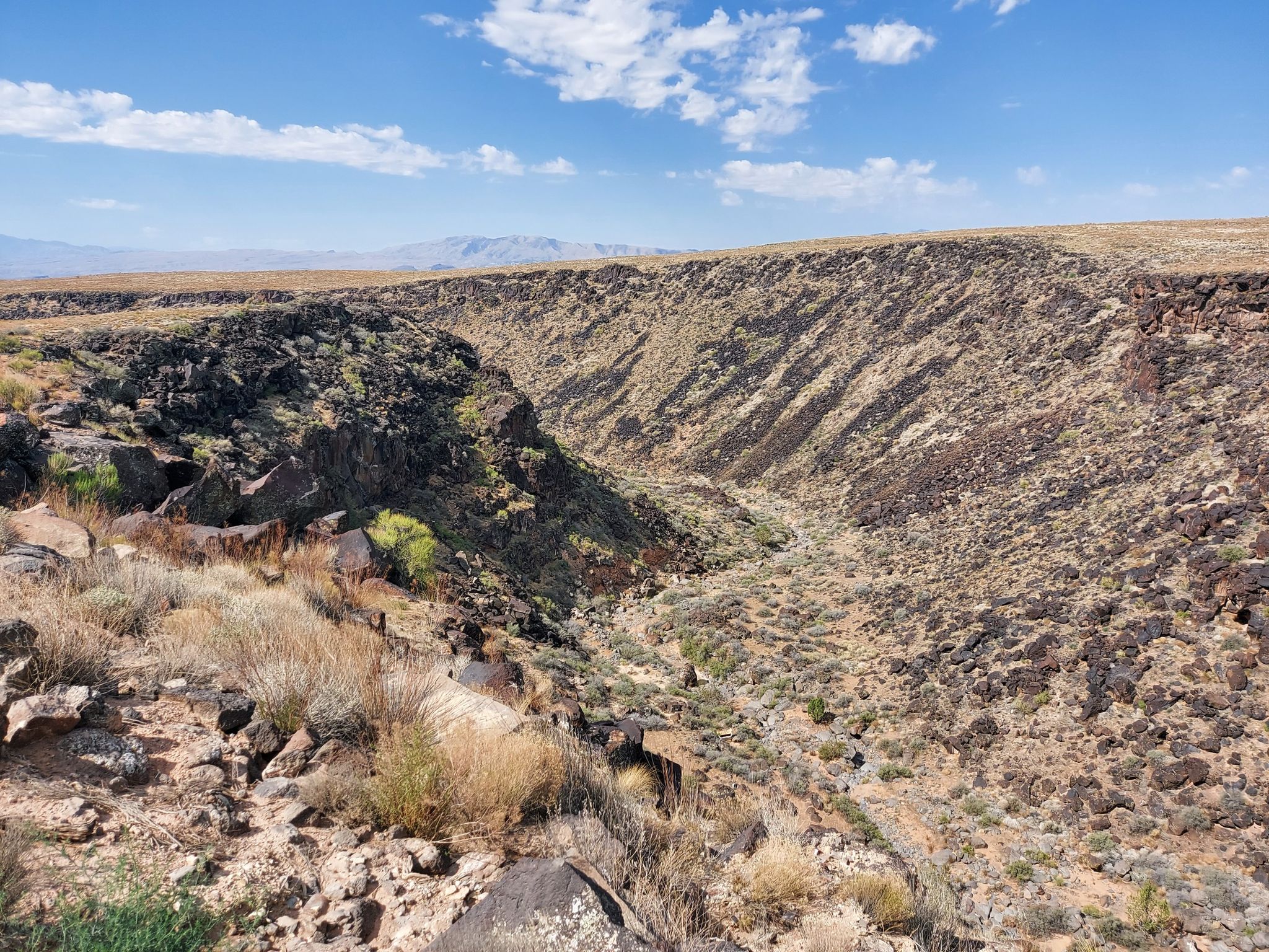 Deep, arid canyon with rocky slopes under a bright blue sky. - Broken Mesa - Ice House Loop