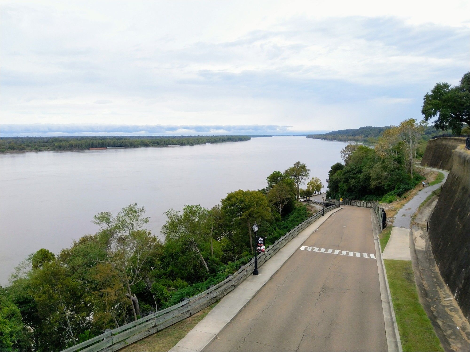 Wide river, paved road, and green trees under an overcast sky. - Pontura Historic House – Stanton Hall loop from Natchez