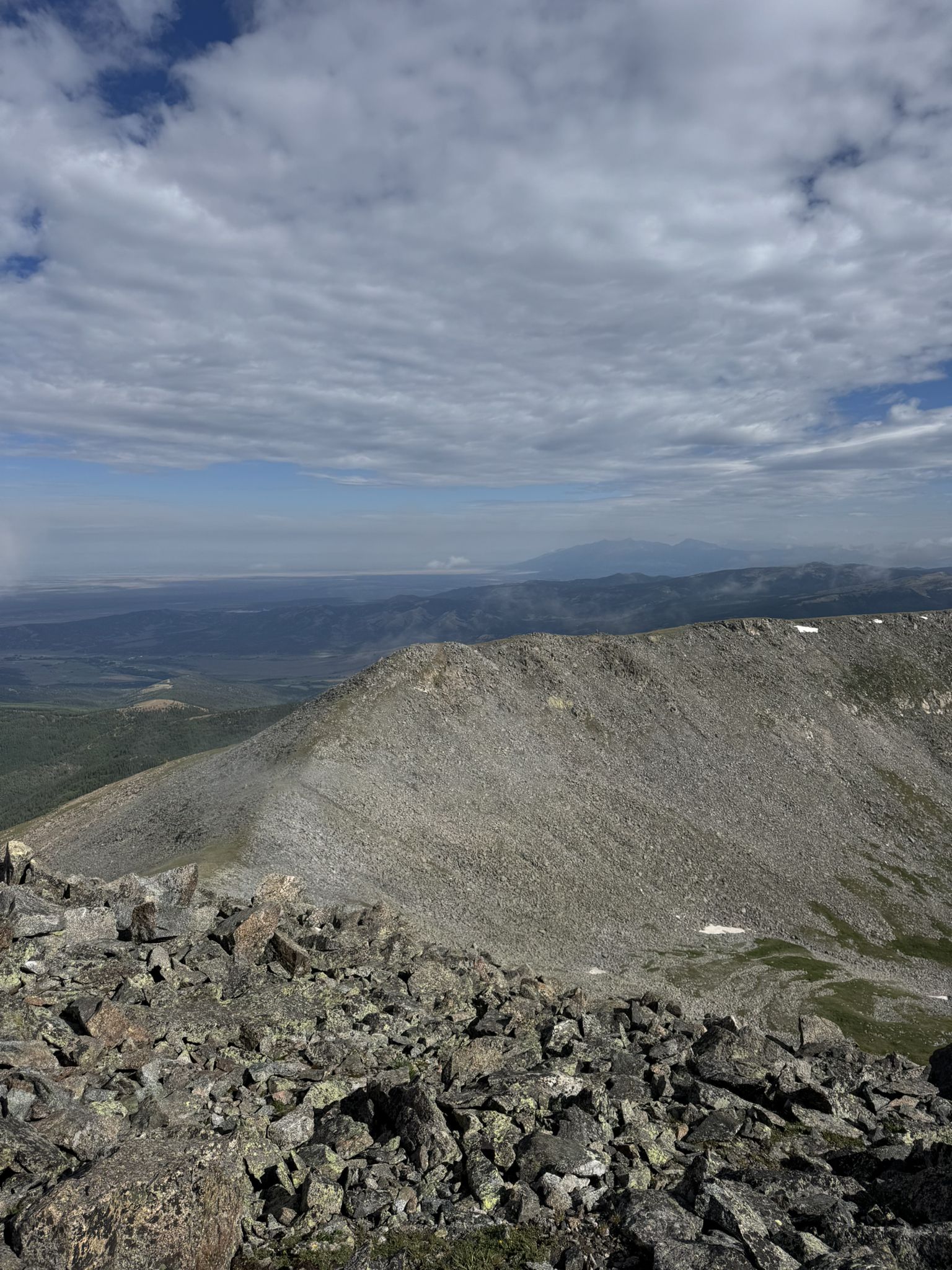 Rocky mountain peak under a cloudy sky, overlooking a vast, distant landscape. - Culebra Peak Trail