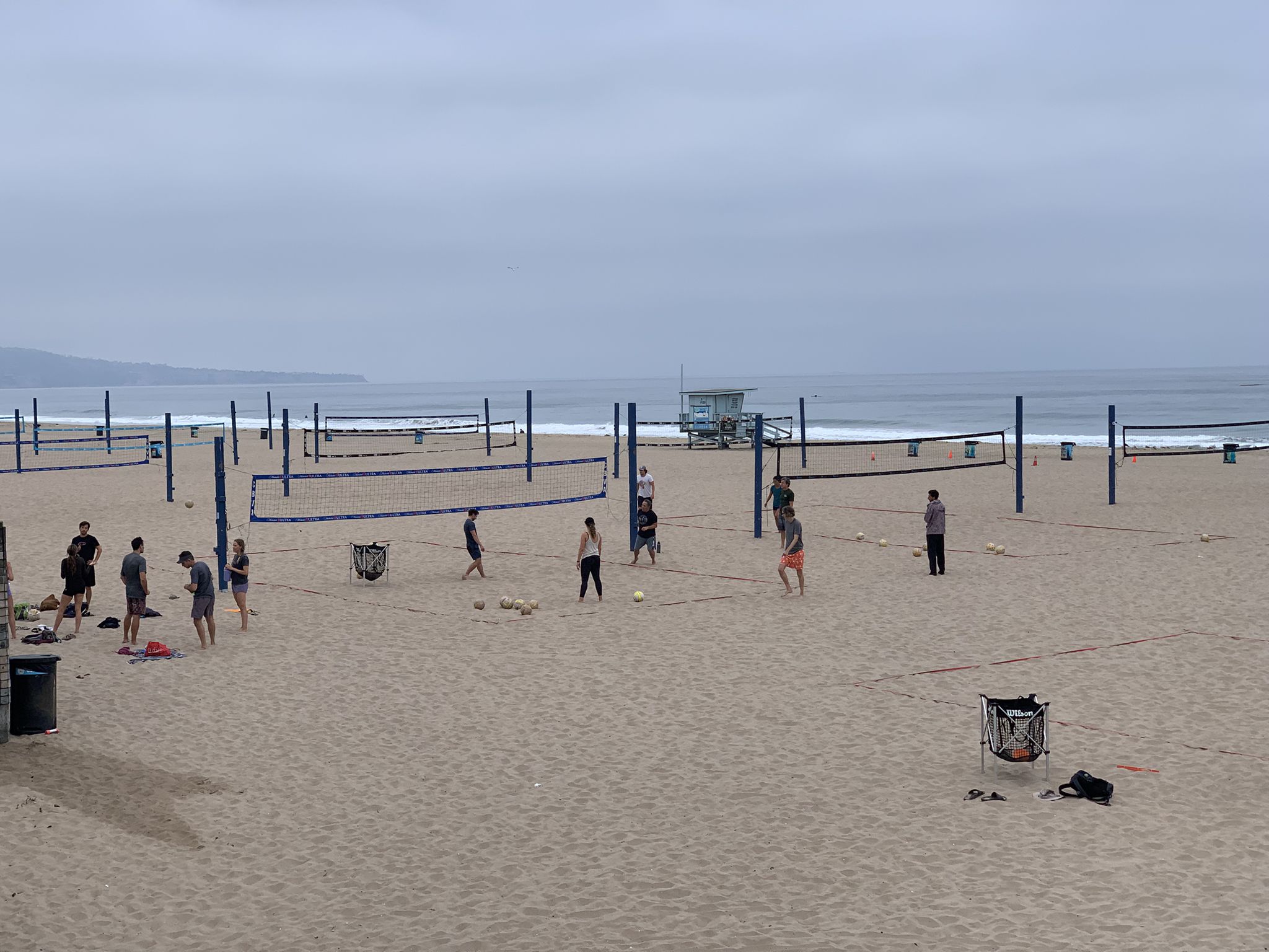 People playing volleyball on sandy courts next to the ocean under an overcast sky. - Noble Park – Manhattan Beach and Pier loop from Manhattan Beach