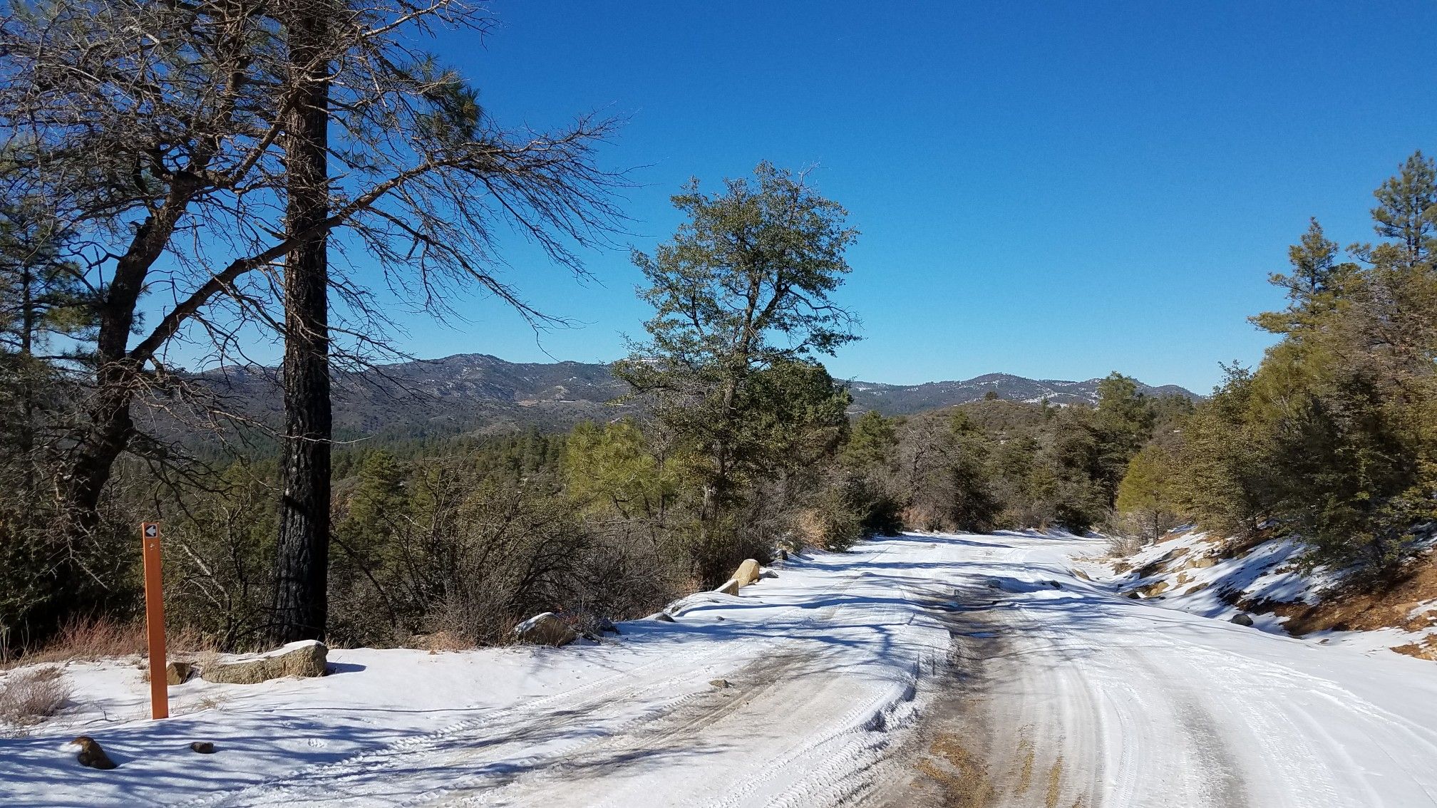 Snowy dirt road overlooking a vast, forested mountain landscape. - Downtown Prescott – Acker Park Trail loop from Prescott