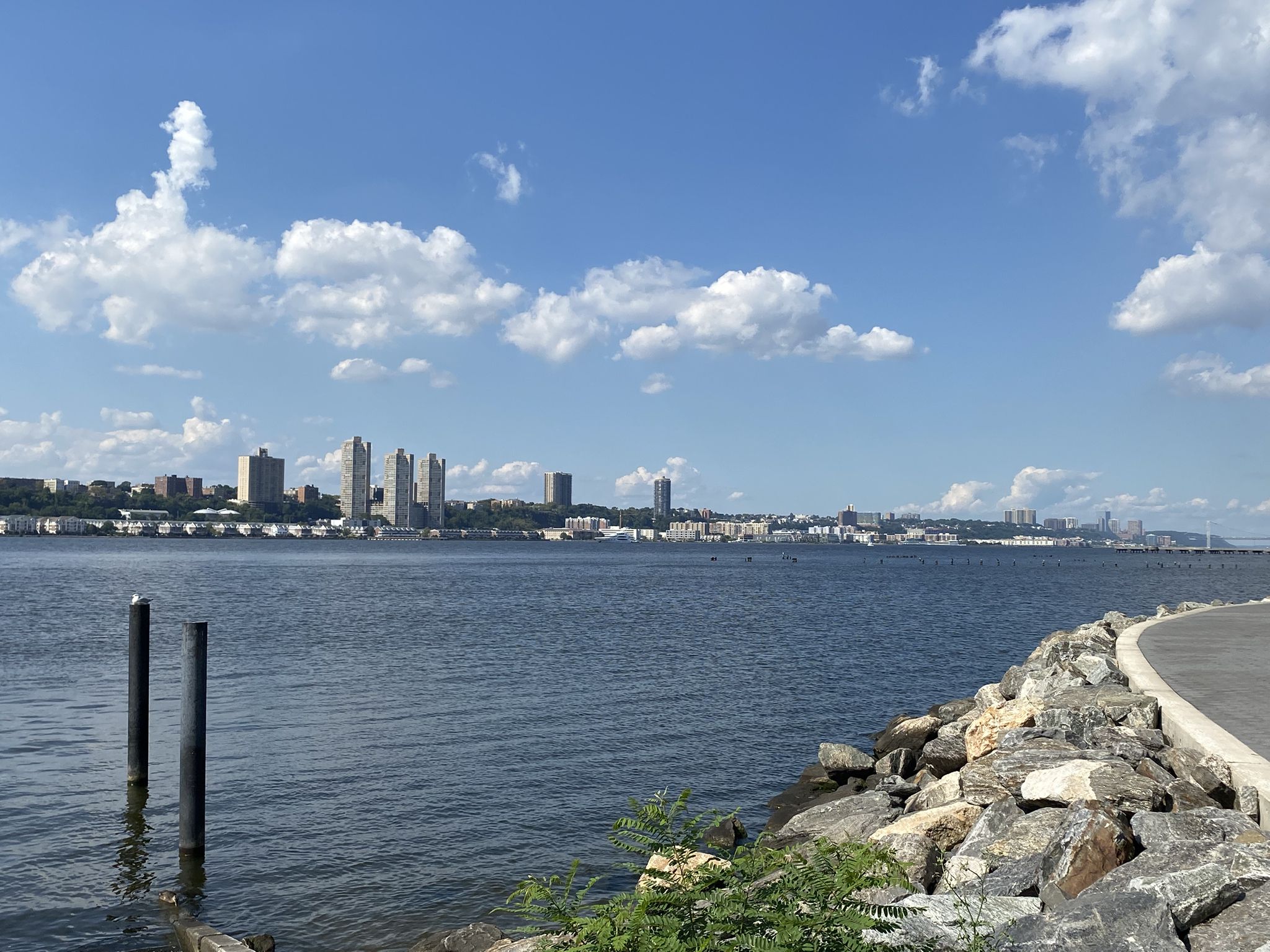 Wide river with distant city skyline under a bright, partly cloudy sky. - Hudson River Greenway