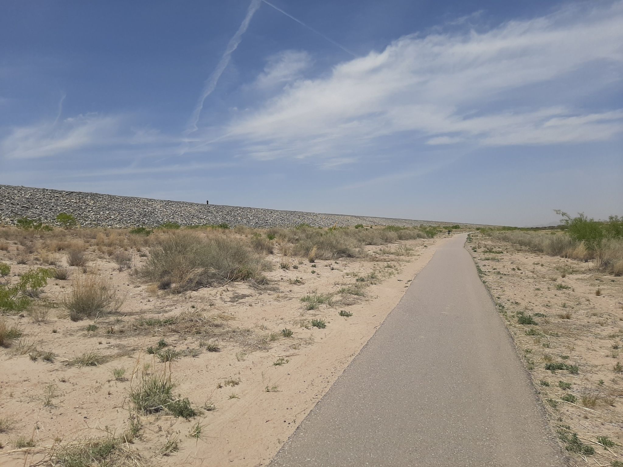 Paved path alongside a rocky embankment in a dry, sunny landscape. - Sagecrest Park loop from Mesilla Valley Mall