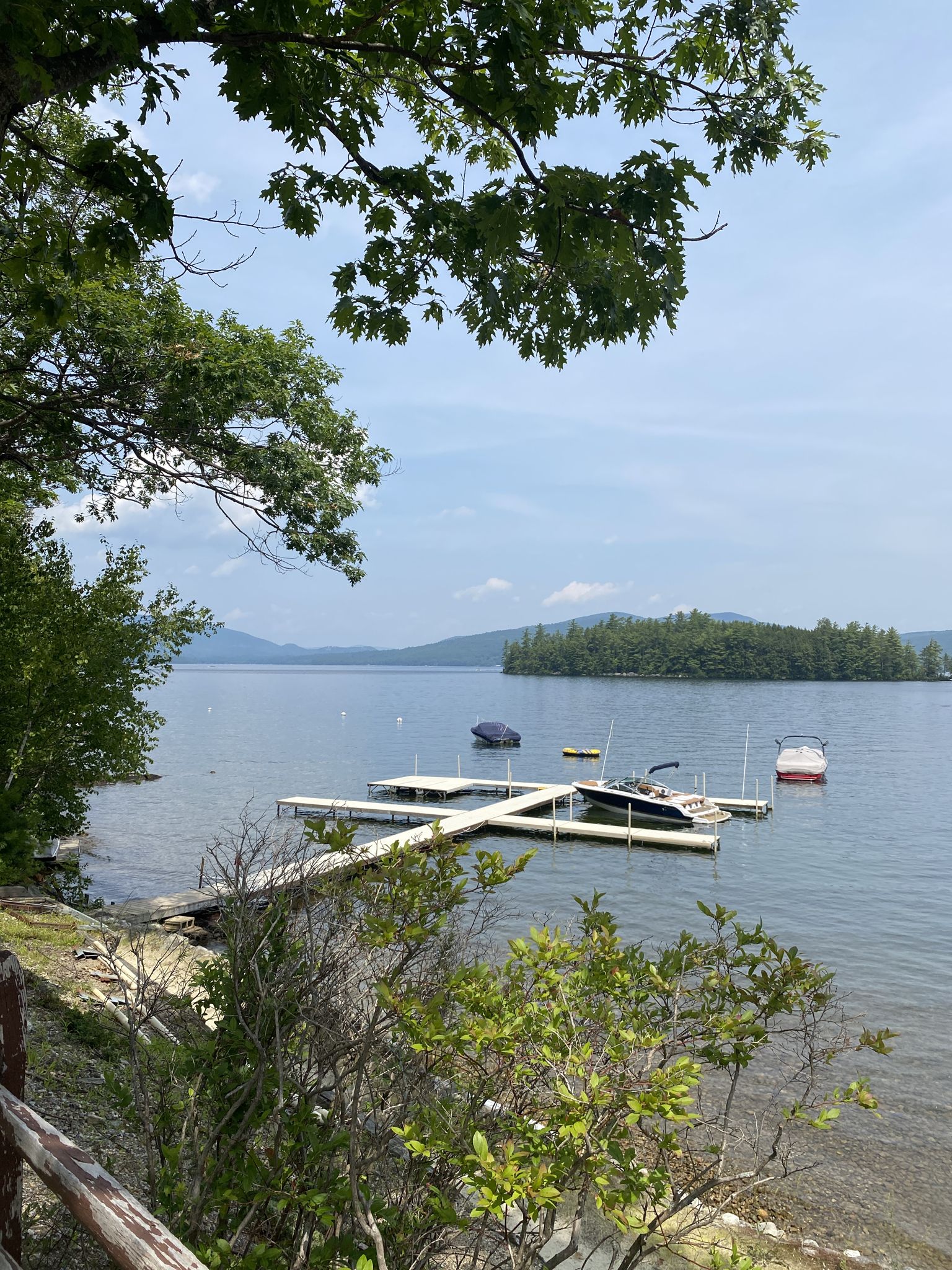 Boats docked at a pier on a calm lake with a distant island. - Newfound Lake loop from Groton via West Shore Road