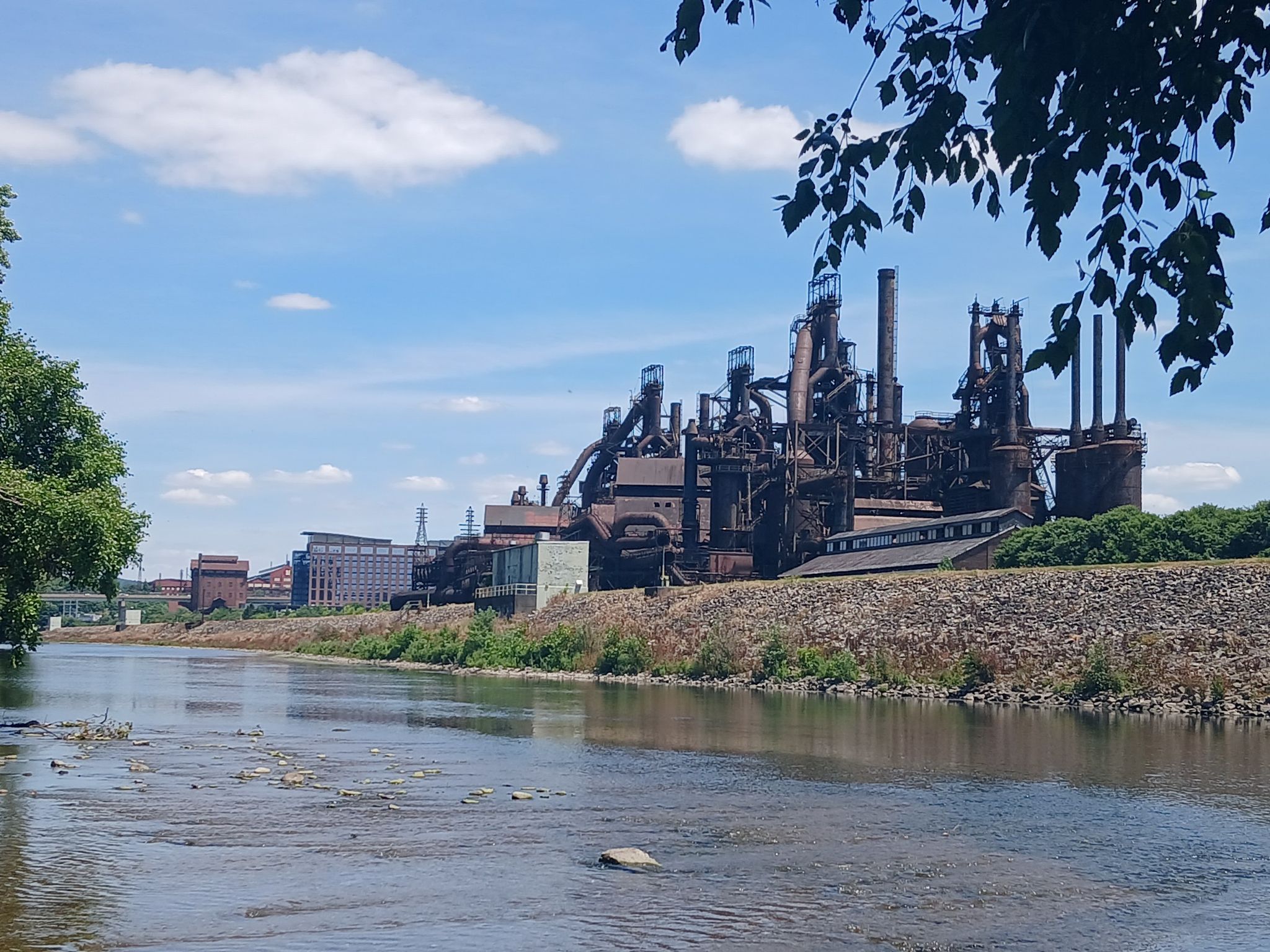 Large industrial complex with smokestacks beside a river under a bright sky. - Delaware Canal State Park – Laubach Island loop from Easton