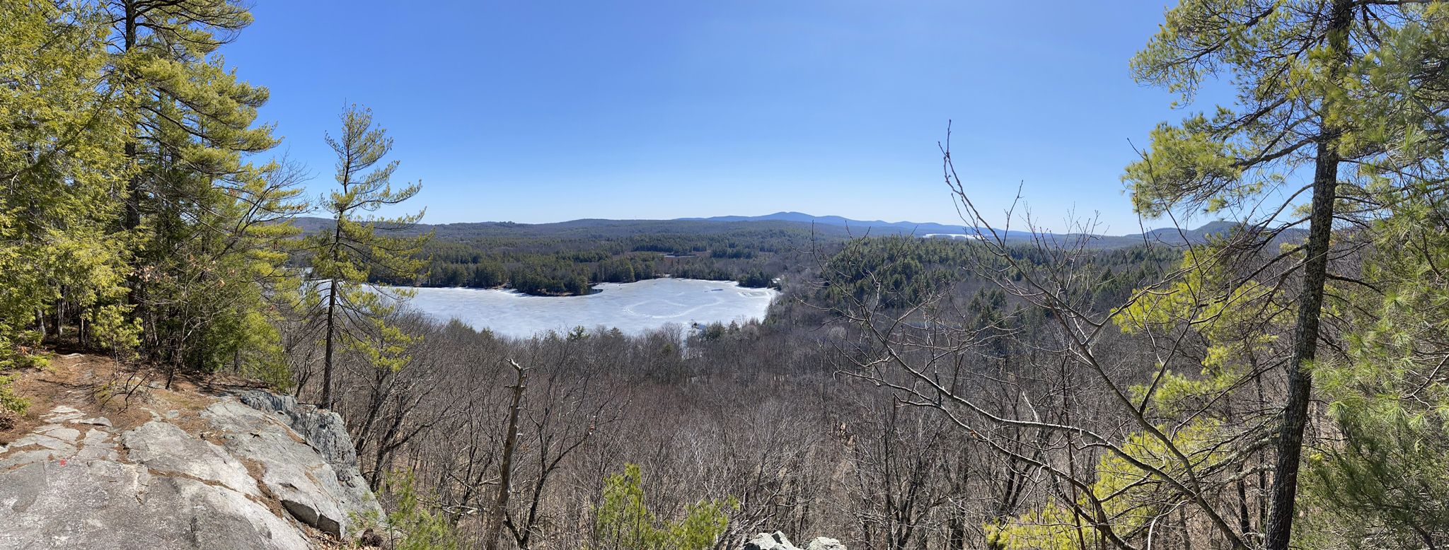 Panoramic view of a partially frozen lake surrounded by forests under a clear sky. - Hamlin Trail loop