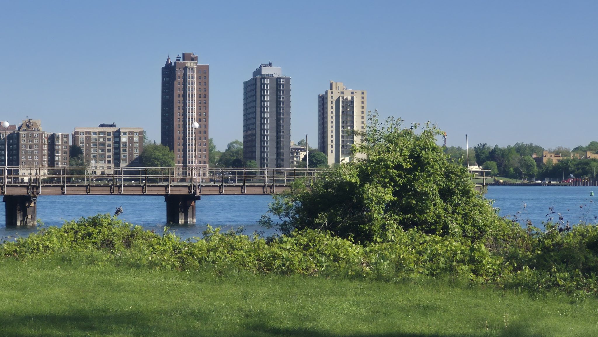 Bridge over water with distant city buildings under a clear sky. - Iron Belle Trail