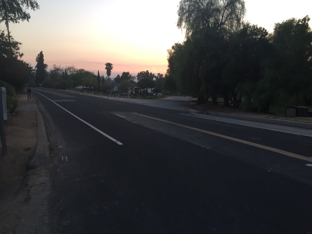 Empty paved road at dusk with trees and distant buildings under a colorful sky. - Roadbike loop from Mill Creek Visitor Center