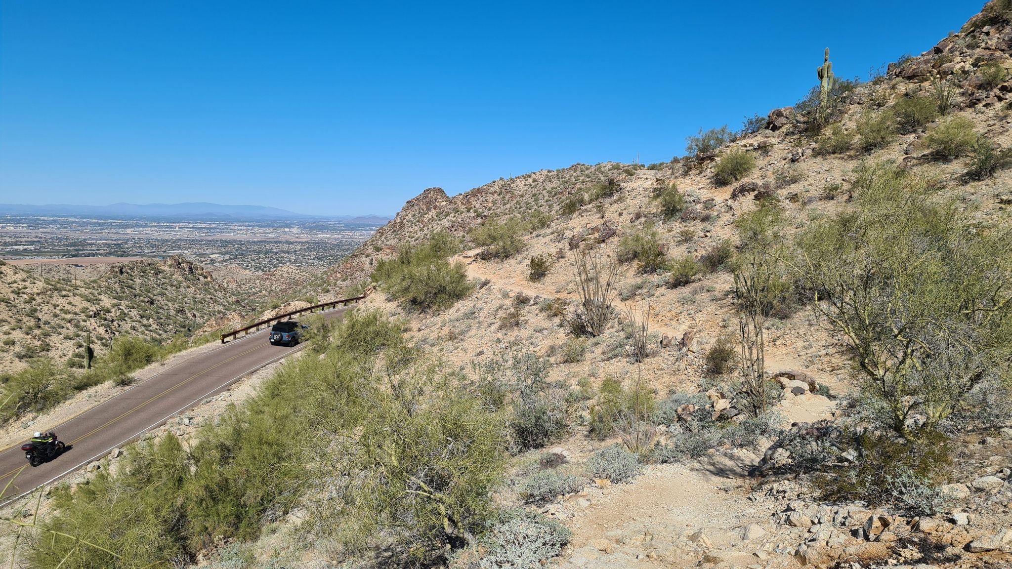 Winding road on a desert hillside with distant city views. - National and Maricopa Trail Loop