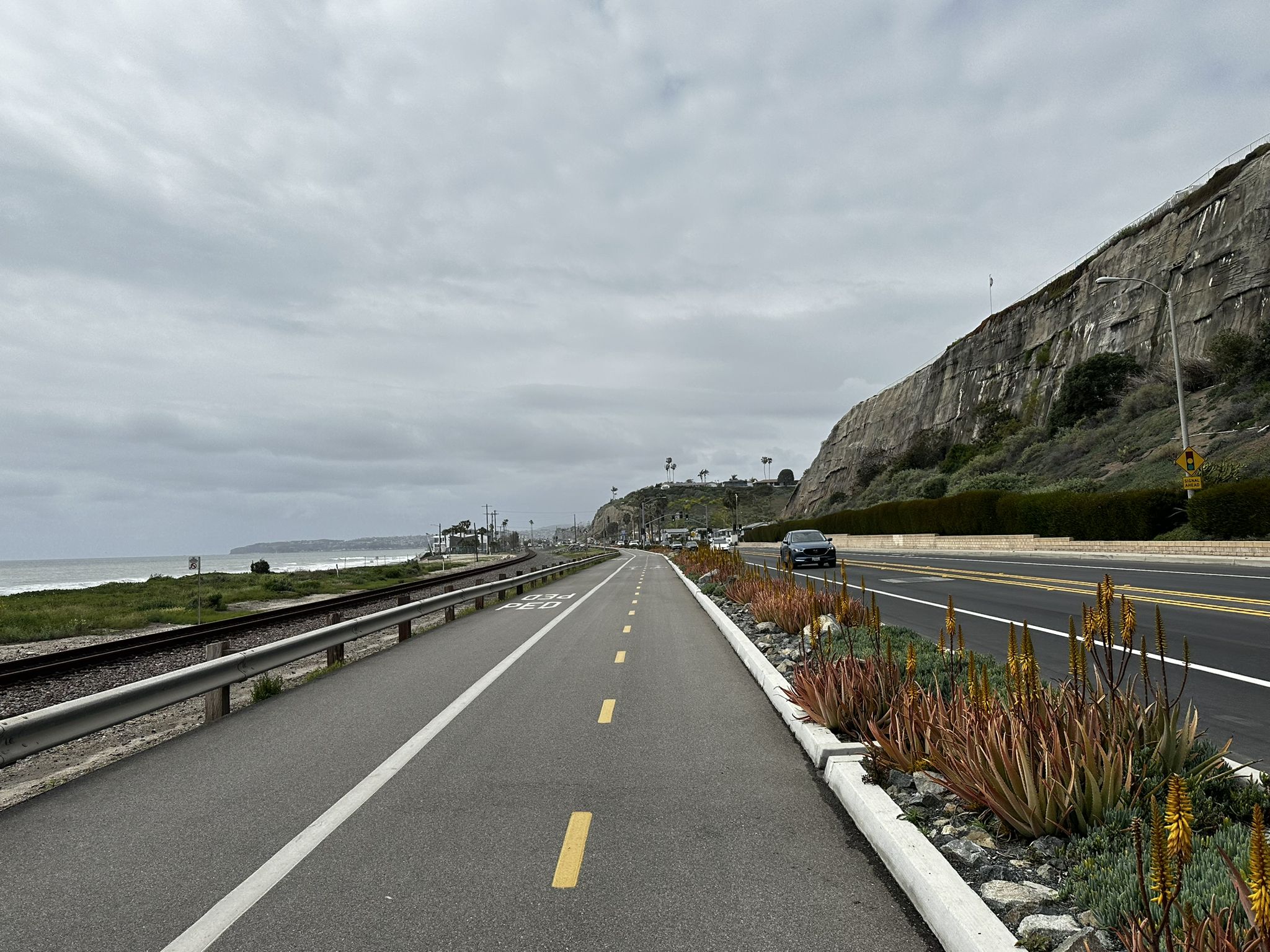 Overcast sky above a coastal road, bike path, and railroad tracks by the ocean. - San Juan Creek Trail and Coastal Loop