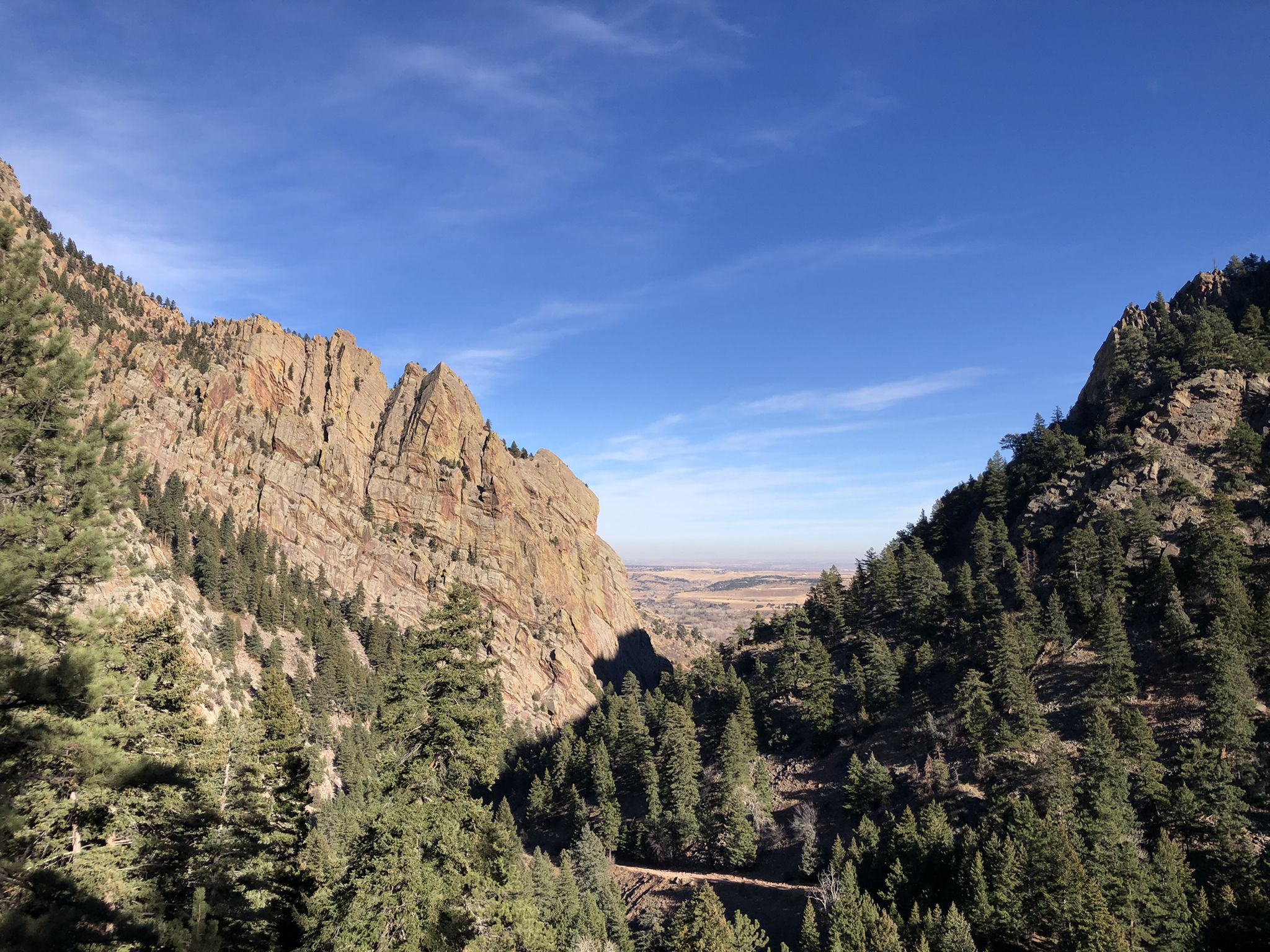 Steep rocky mountainsides and pine trees framing a distant valley on a clear day. - Rattlesnake Gulch Trail loop from Eldorado Mountain