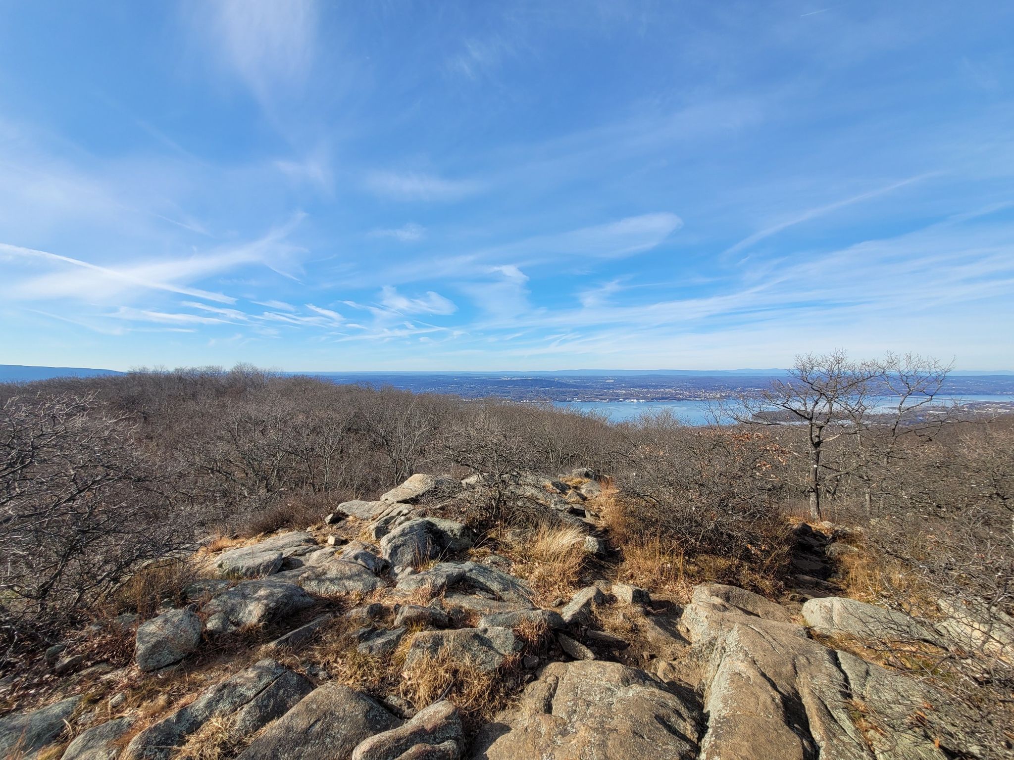 Rocky hilltop with bare trees, overlooking a distant body of water under blue sky. - Ridge views – Railway Station Cold Spring loop from Cold Spring