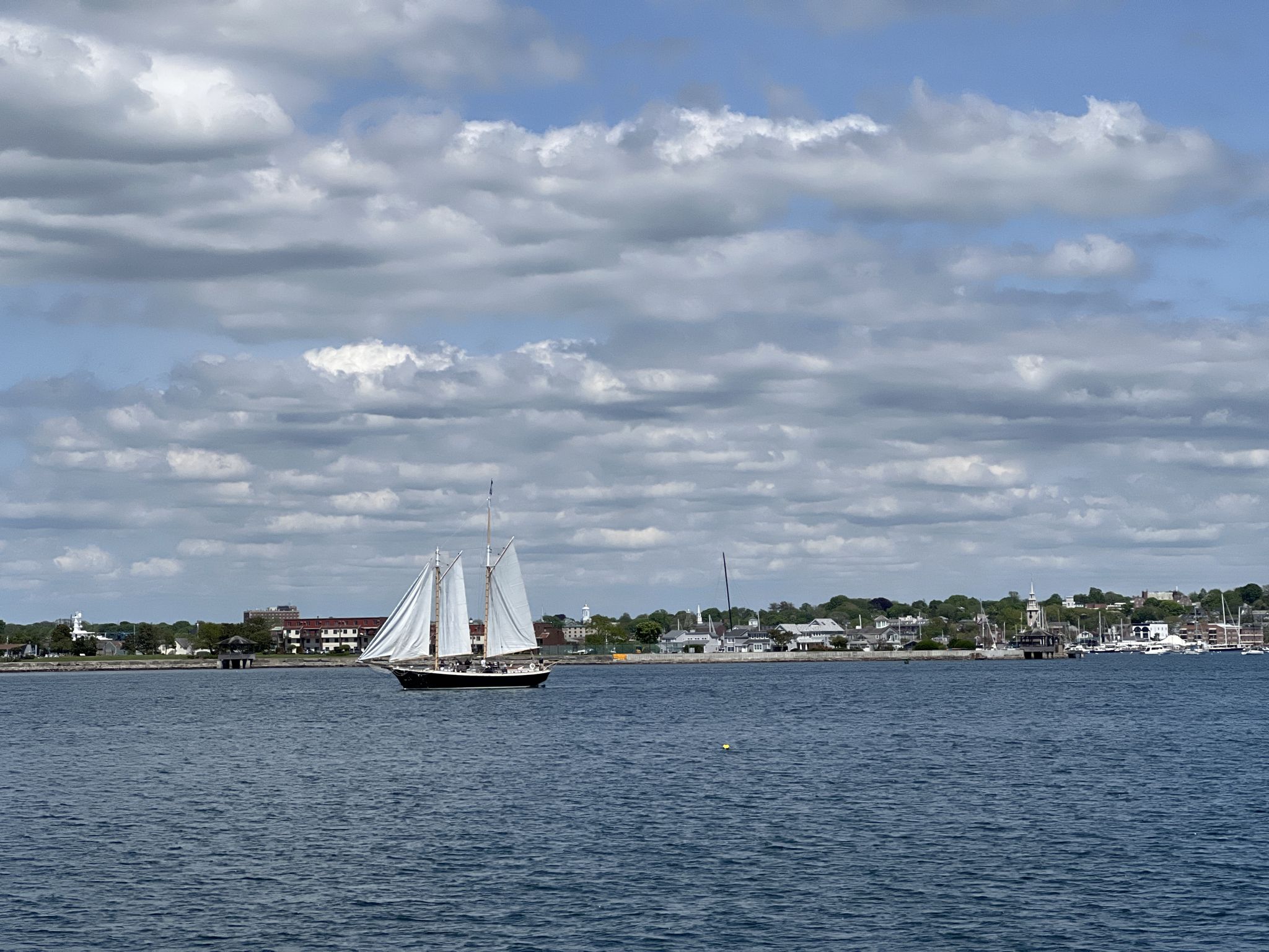Large sailboat on blue water with a distant town under a cloudy sky. - Portuguese Discovery Monument – Fort Adams State Park loop from Fort Adams State Park
