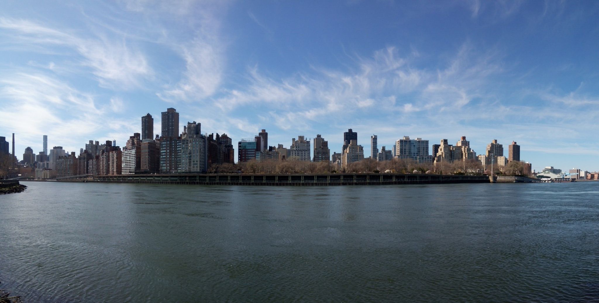 Panoramic view of a city skyline across a wide river on a clear day. - Roosevelt Island Tramway – Roosevelt Island Lighthouse loop from Roosevelt Island