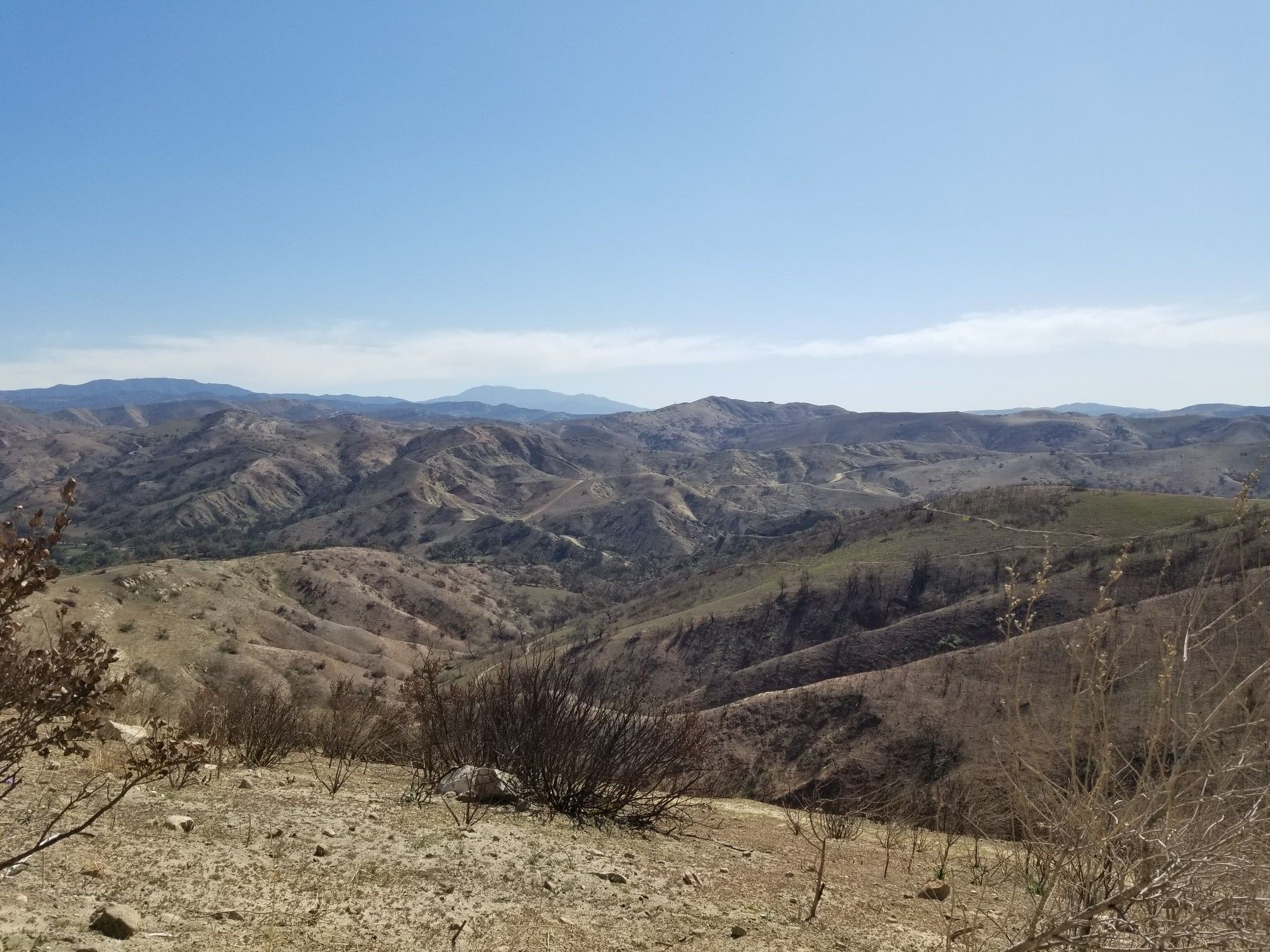 Expansive view of dry, rolling hills and valleys under a hazy blue sky. - Deer Trail and Robber's Peak Loop