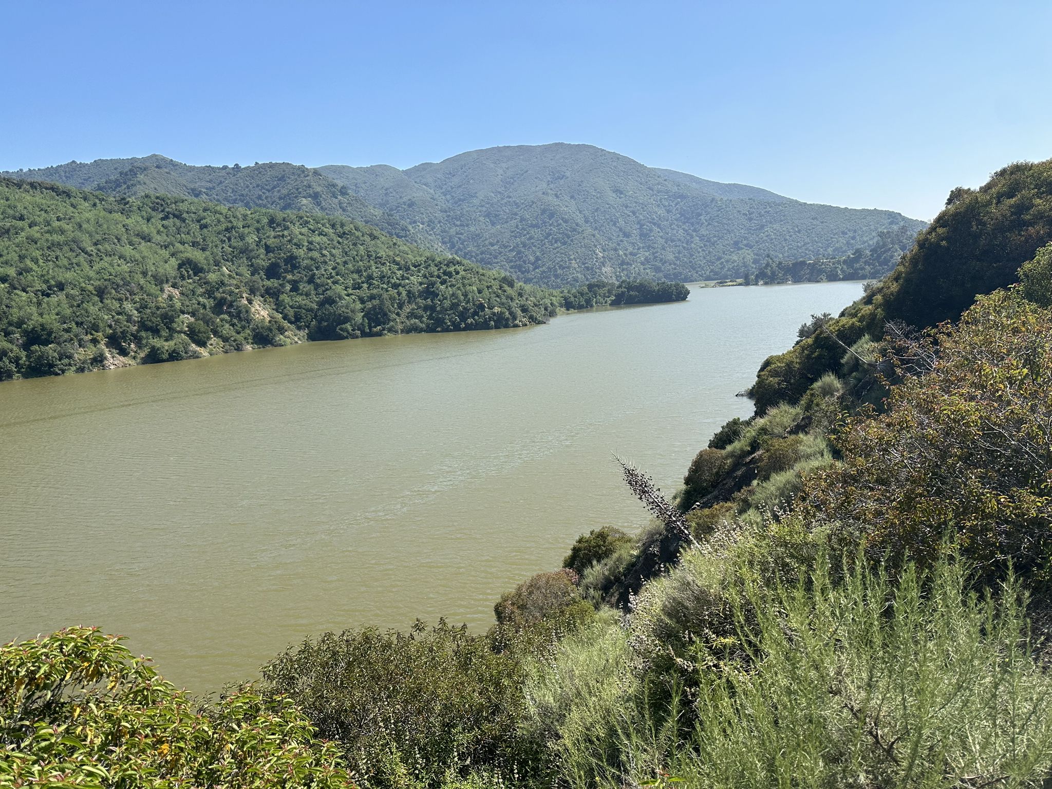 Wide body of water surrounded by lush green forested mountains under bright sun. - San Gabriel Canyon Road & Mt Baldy loop from Lario Staging Area