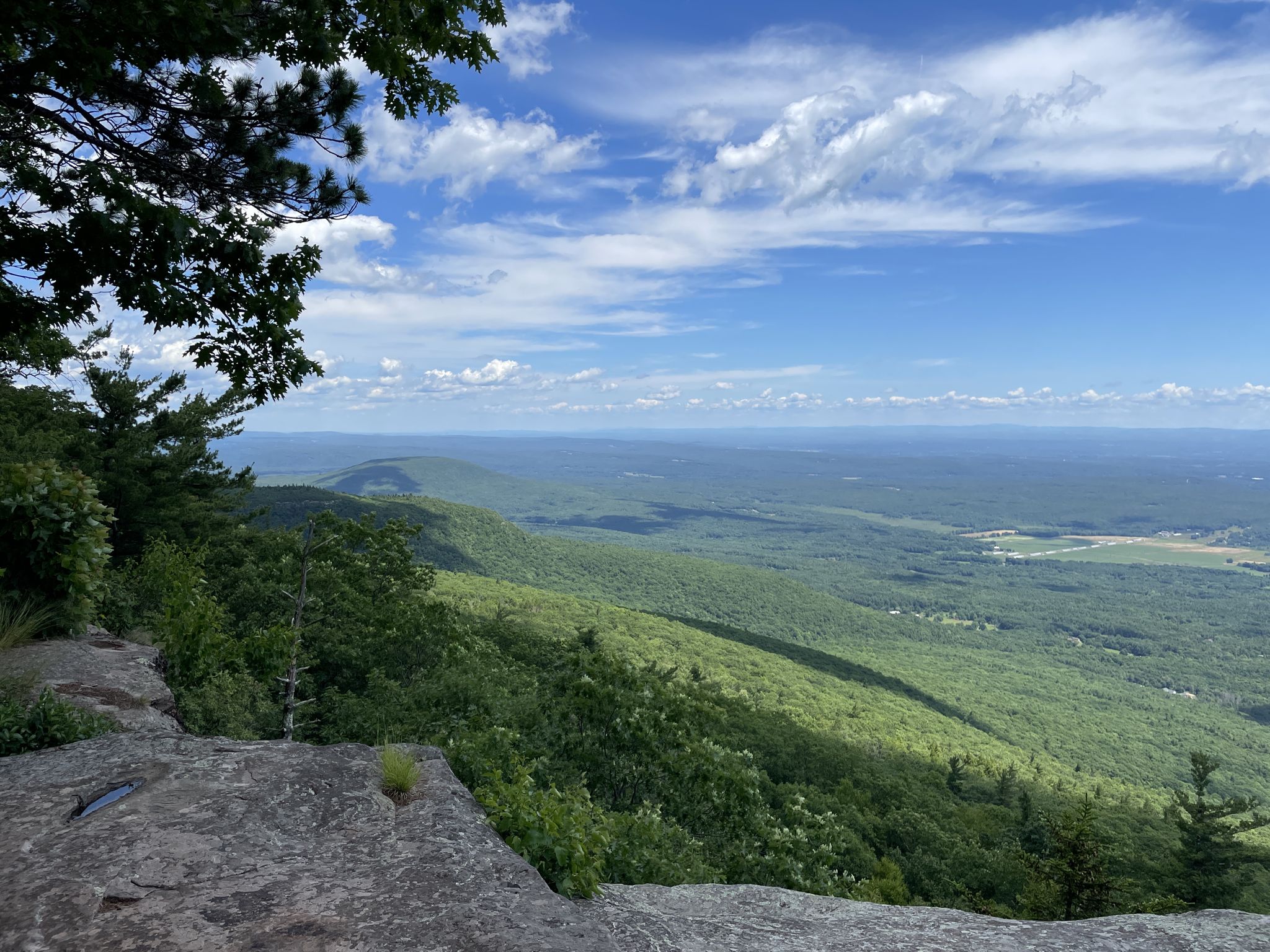 Panoramic view of a green valley from a rocky cliff under blue sky. - Escarpment, Rock Shelter, and Mary's Glen Trail Loop