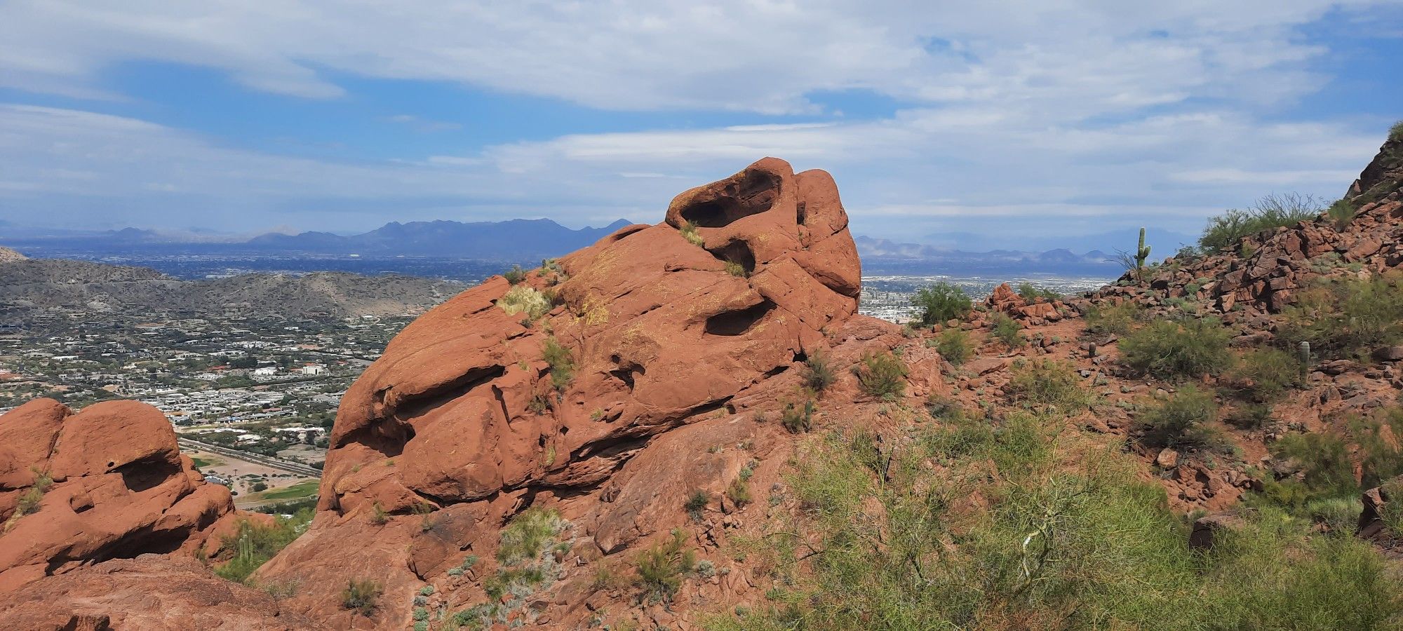 Large red rock formations on a hillside overlooking a city, sunny day. - Camelback Mountain via Echo Canyon Trail – Scottsdale, Arizona