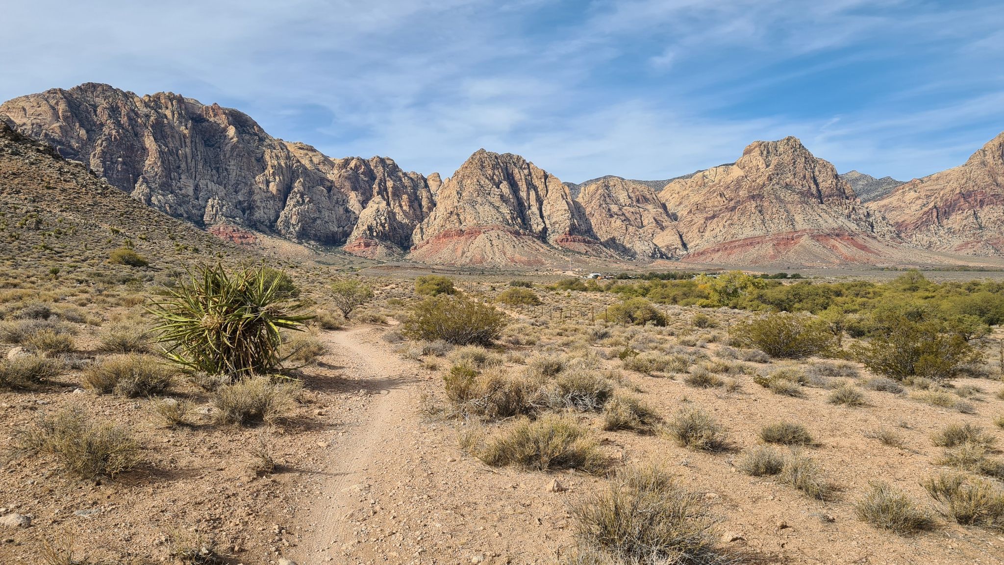 Desert trail leads to large, colorful mountains under a partly cloudy sky. - The Hurl and Landmine Loop