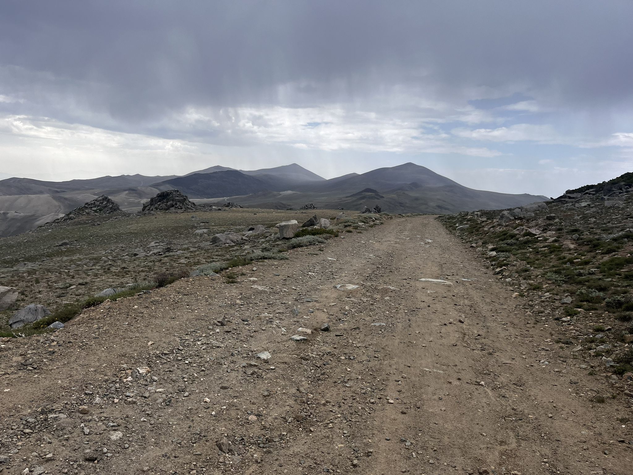 Dirt road through a rocky, sparse landscape under a cloudy sky. - White Mountain Trailhead loop from Barcroft White Mountain Research Station