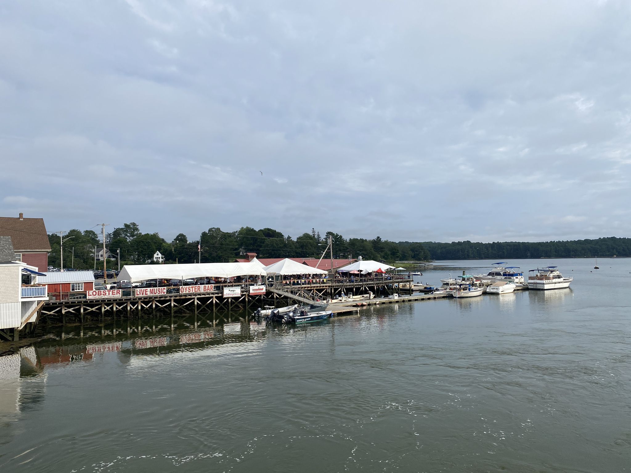 Waterfront buildings and boats on calm water under an overcast sky. - Twin Villages to Pemaquid Lighthouse & Fort William Henry loop