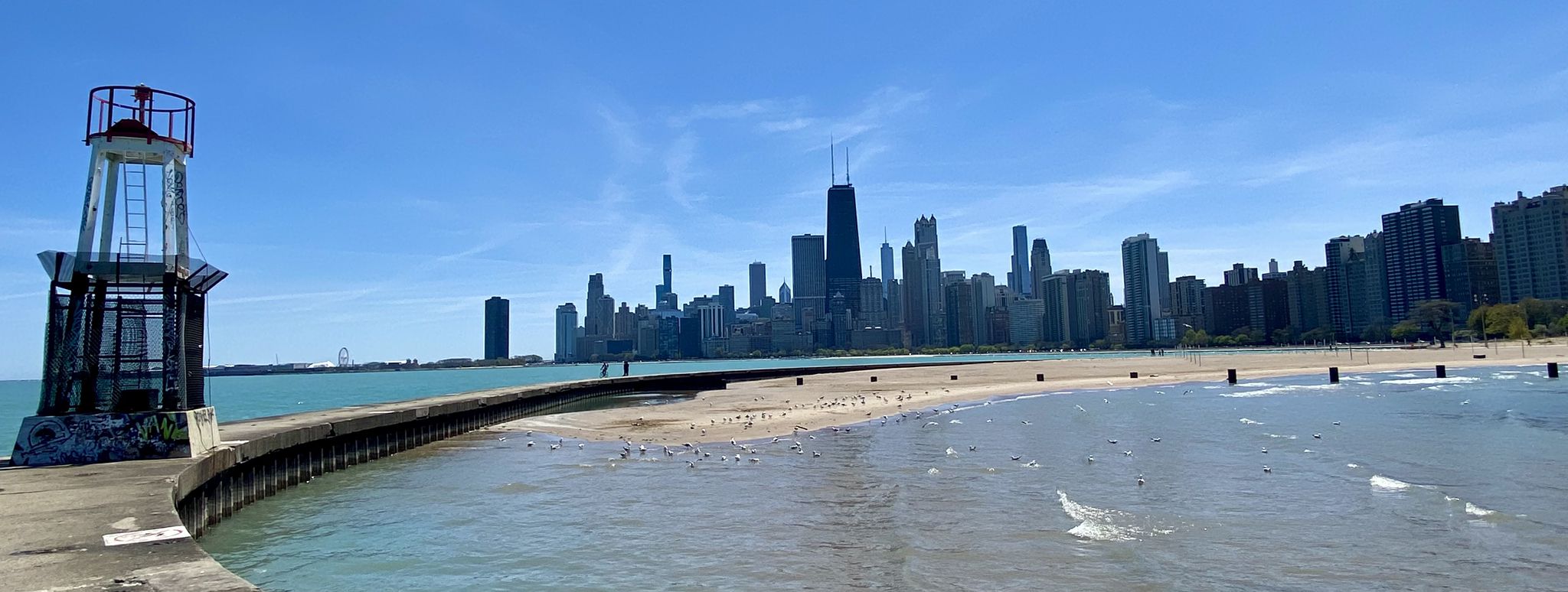 Lighthouse and pier leading to a city skyline and beach on a clear day. - Lakefront Trail: North Avenue Beach to Navy Pier