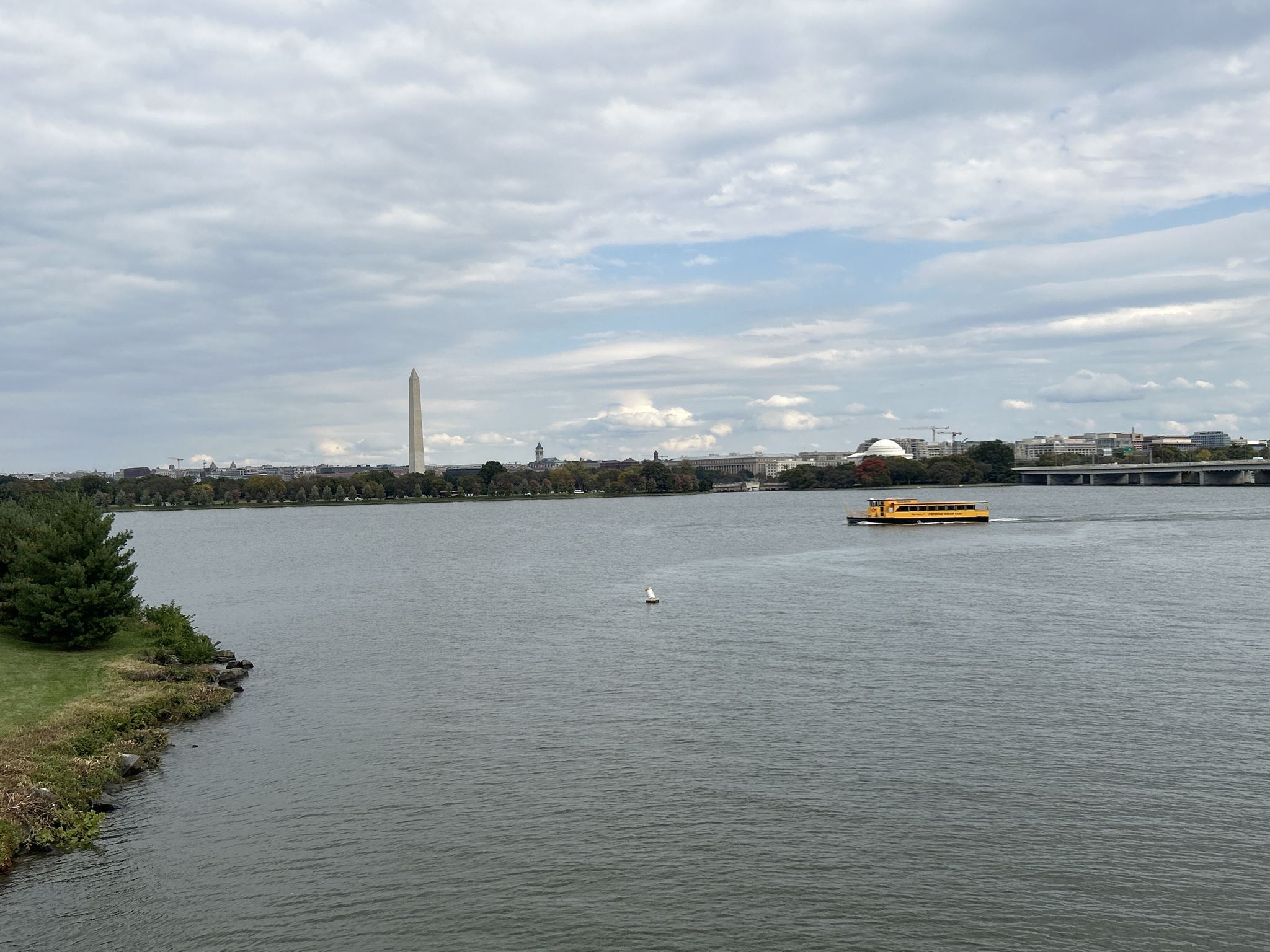 Overcast view of water with distant monument and yellow boat. - Custis, Washington-Old Dominion, and Mount Vernon Trail Loop