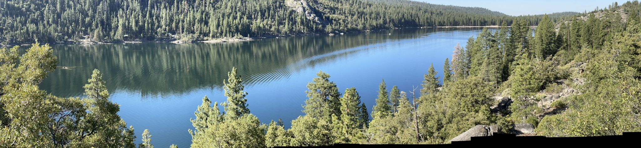 Panoramic view of a calm lake surrounded by dense green forest on a sunny day. - Herring Creek and Pinecrest Lake Loop