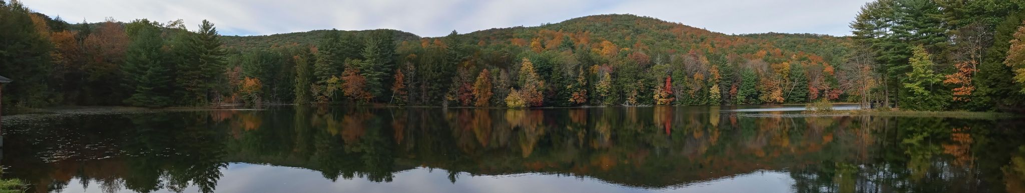 Panoramic view of a calm lake reflecting colorful autumn hills under a soft sky. - Lithia Springs Reservoir Loop