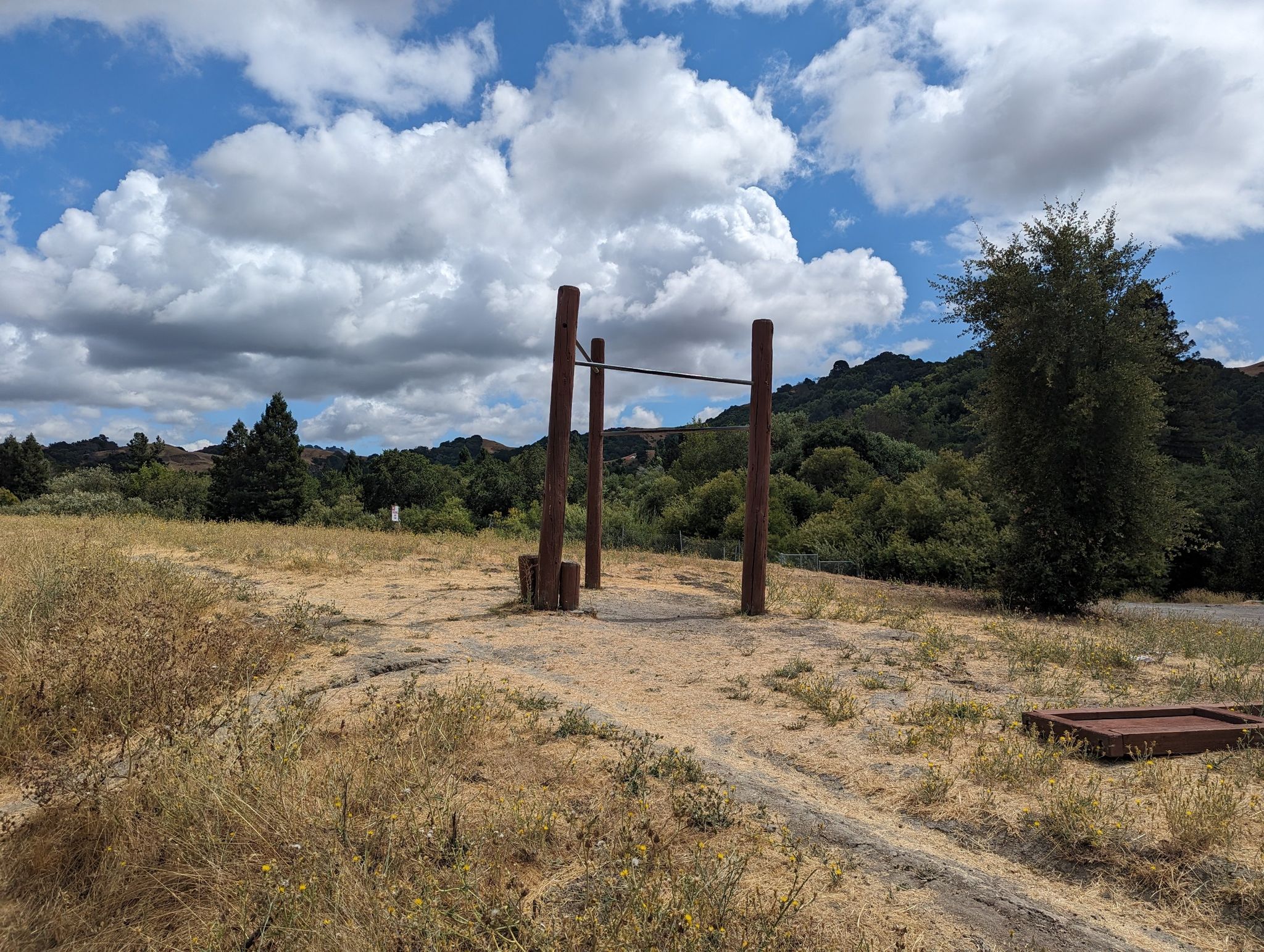 Outdoor exercise bars in a dry grassy field under a cloudy blue sky. - Lafayette-Moraga Regional Trail