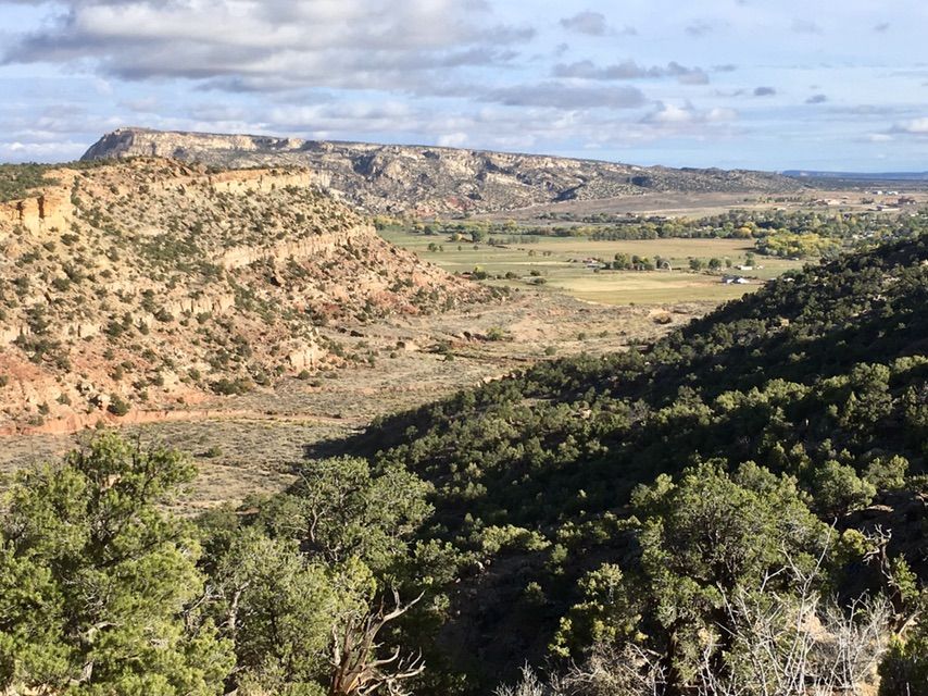 Expansive valley with green fields, rocky hills, and distant mountains. - Mountainbike loop from Escalante