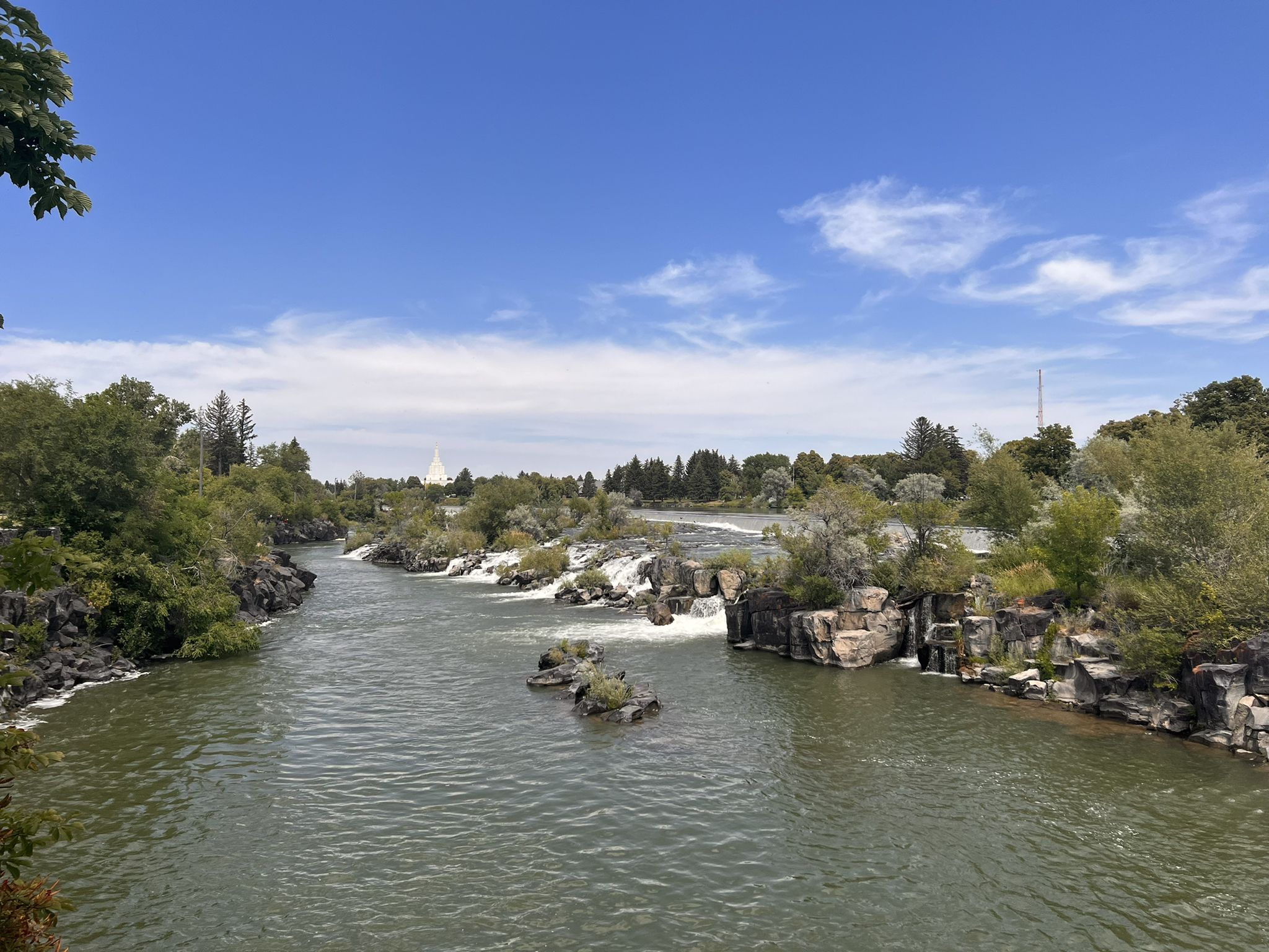 River with rapids, rocky banks, and lush trees under a bright blue sky. - Idaho Falls Greenbelt loop